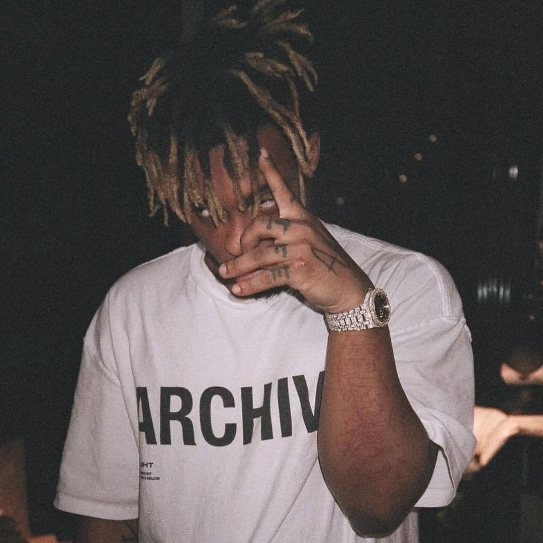 辮子紋身男子在夜晚穿著白色T恤和鑽石手錶做出和平手勢。 — Juice Wrld 壁紙