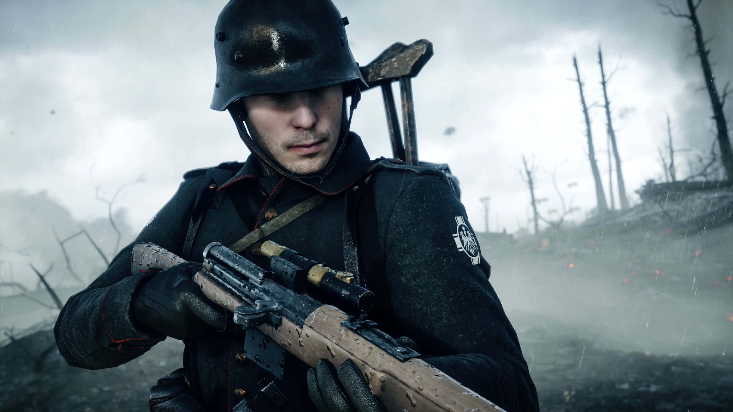 World War 2 桌布 壁紙 — 一名陰沉的士兵，戴著泥濘的頭盔和制服，在雨淋的戰場上，枯樹和煙霧中緊握步槍。