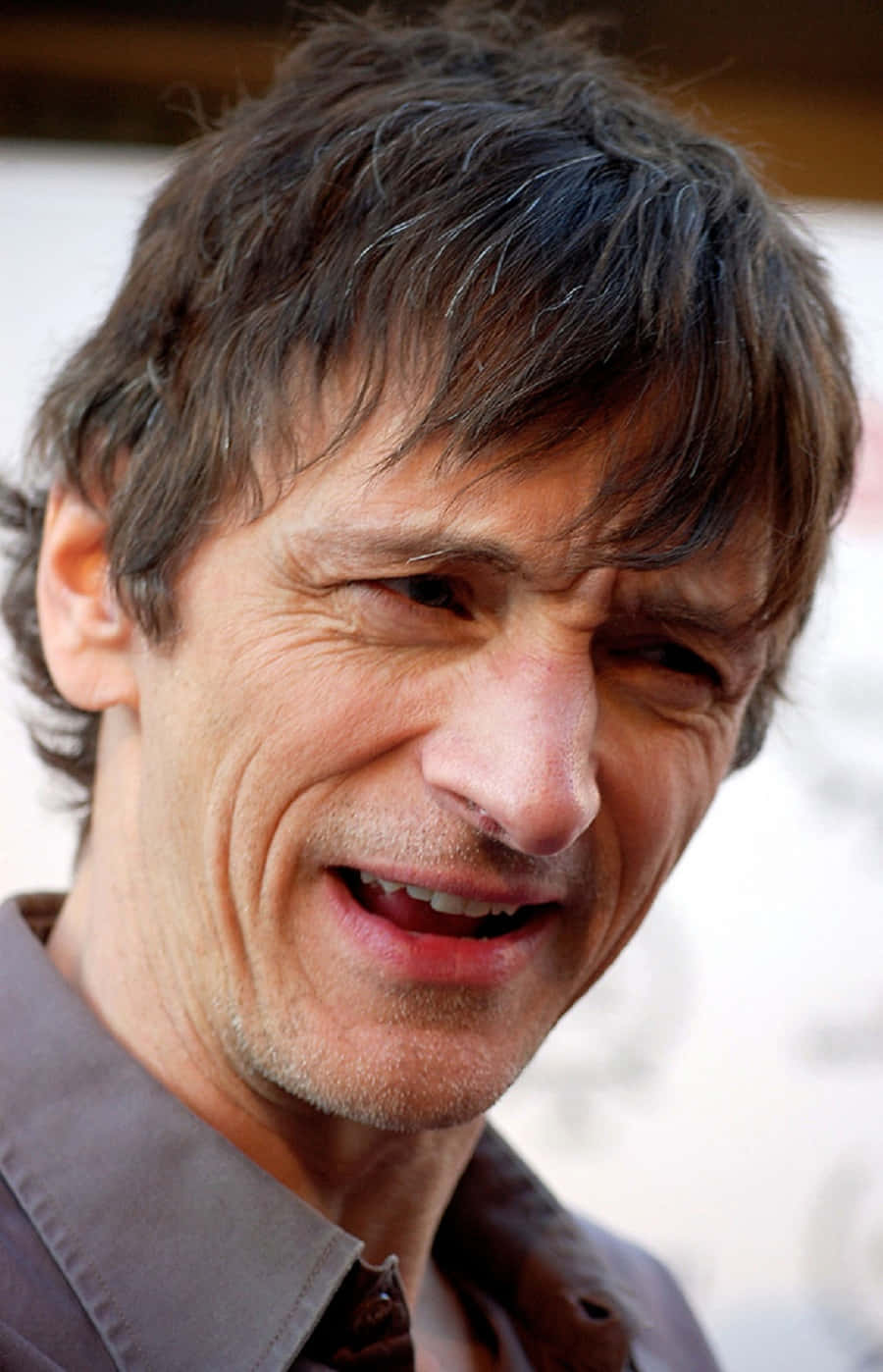 John Hawkes 桌布 壁紙 — 一名頭髮凌亂深色、露出溫暖笑容露出牙齒的男士特寫照片。