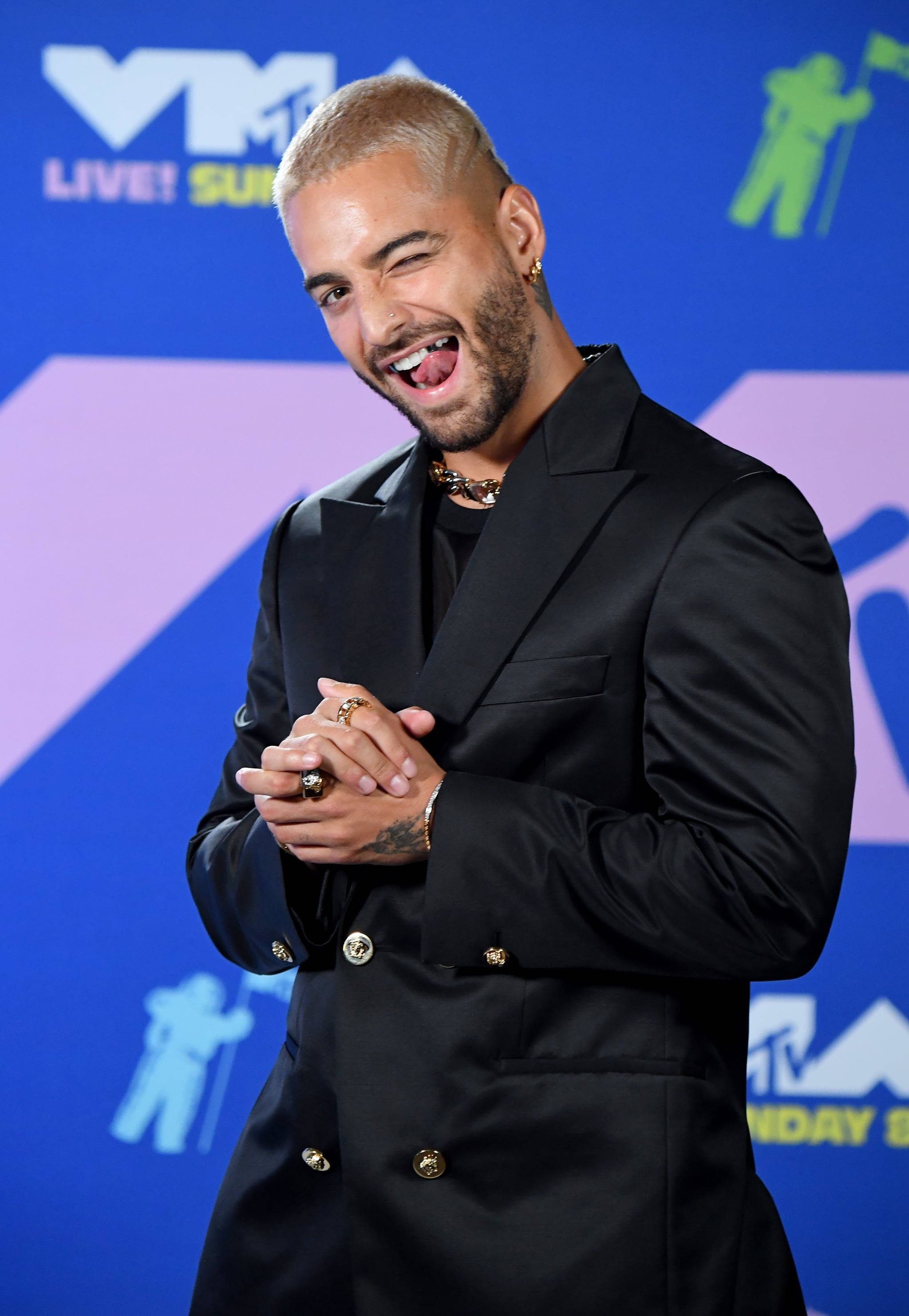 Maluma 桌布 壁紙 — 一名頭髮和鬍子漂白了的男人在MTV活動中穿著黑色雙排扣西裝開心地笑著。