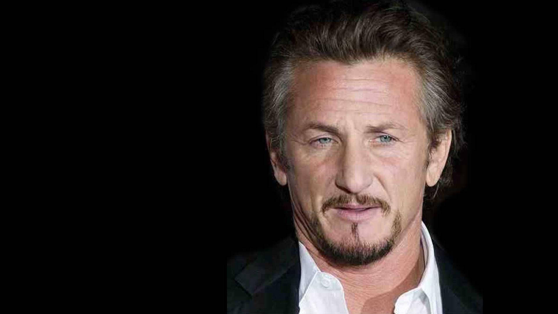 Sean Penn 桌布 壁紙 — 一名頭髮花白、留著山羊鬍的男人穿著黑色西裝和白色襯衫，在黑色背景前的特寫肖像。
