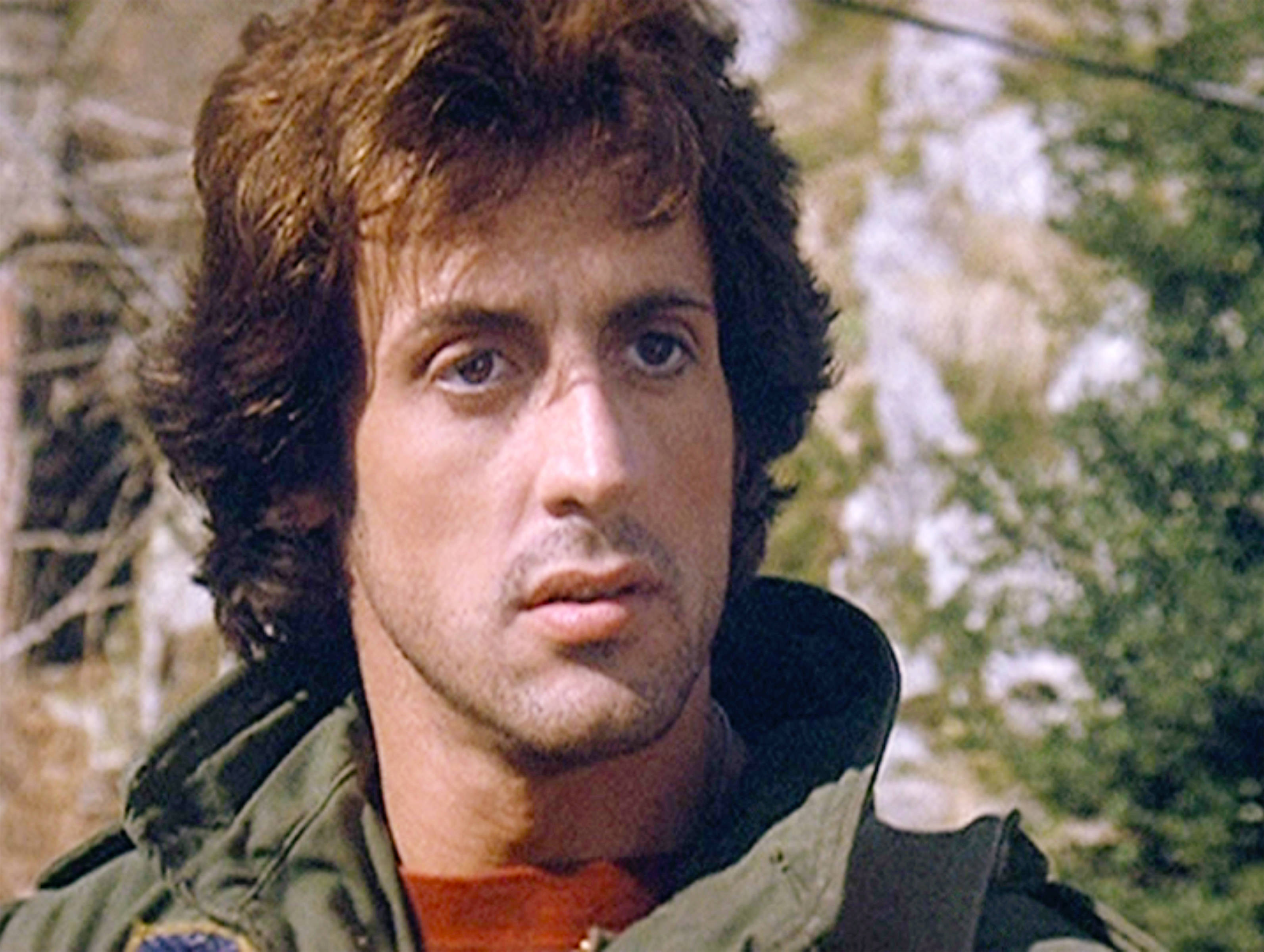rocky 桌布 壁紙 — 一名頭髮蓬鬆棕色、眼神銳利的男子穿著綠色外套，背景是模糊的森林特寫。