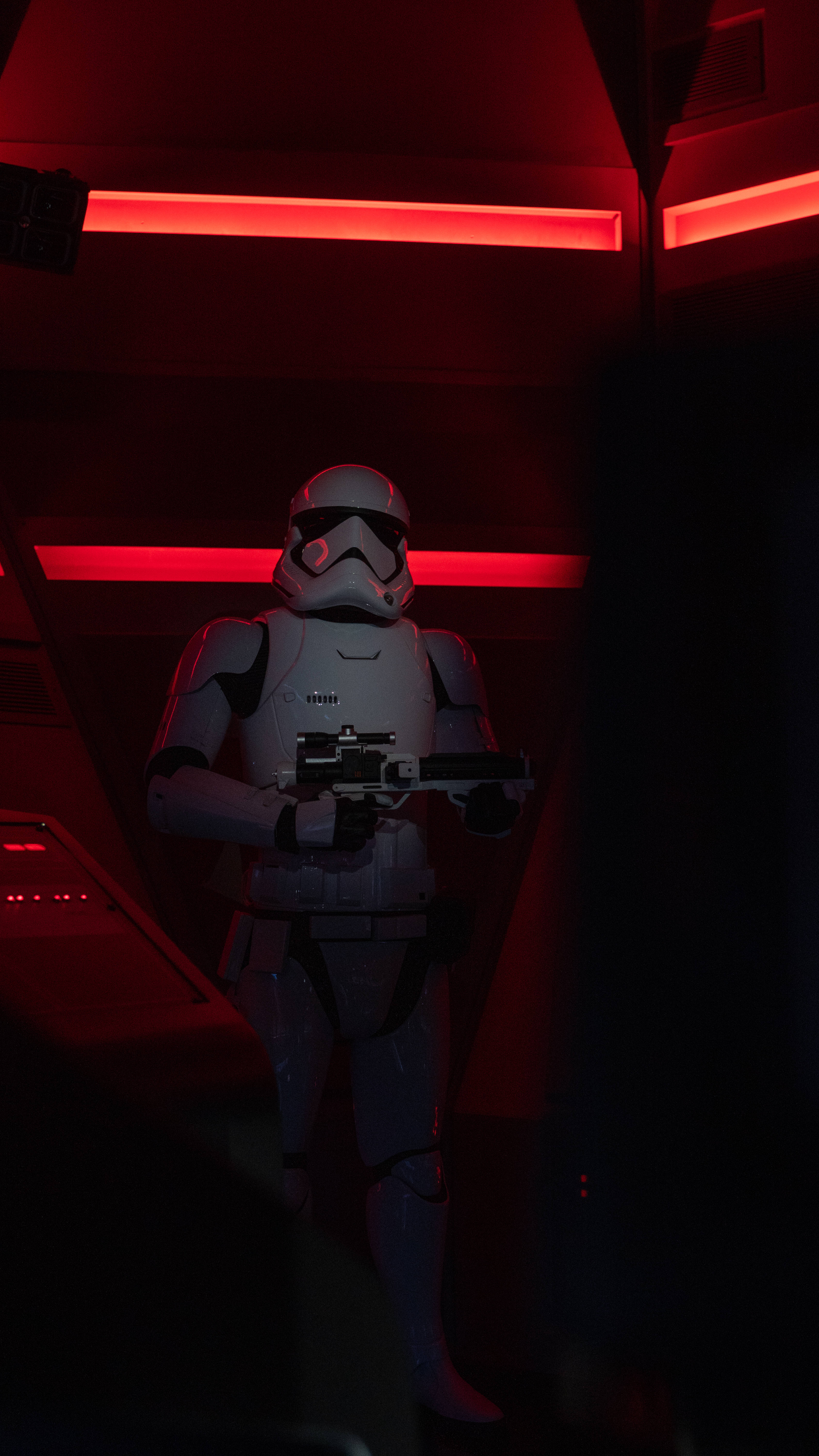 Star Wars Red 桌布 壁紙 — 一名風暴兵在昏暗的走廊中保持警覺，被紅色應急燈光籠罩，手持爆能槍。