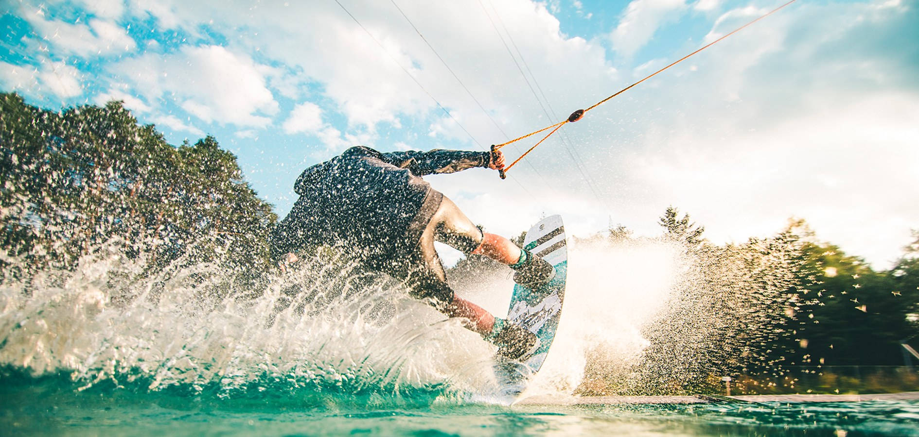 surfing 桌布 壁紙 — 一名風箏衝浪者騎乘著碧綠色的海浪，水花四濺，陽光照耀的雲朵在頭頂飄移。