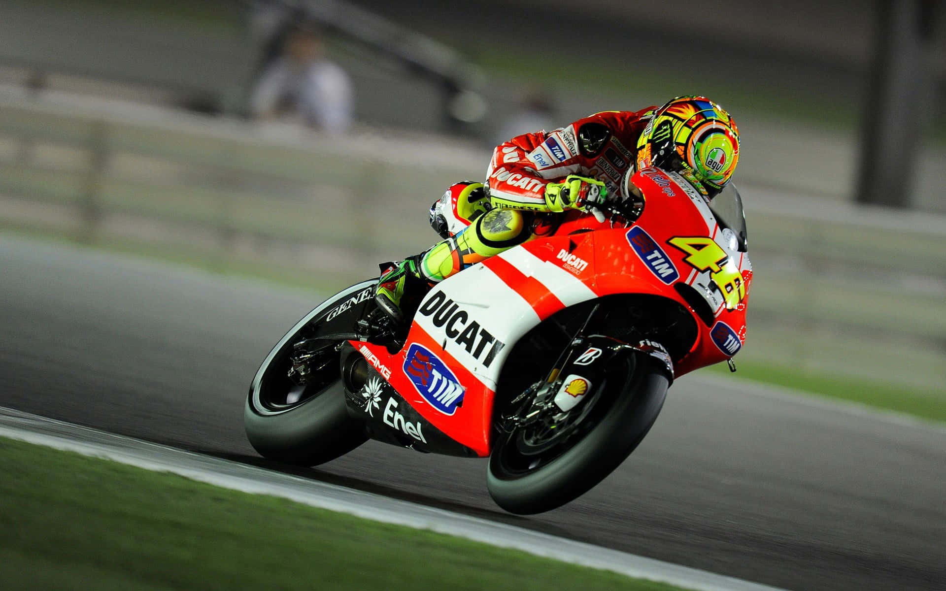 Motorsport 桌布 壁紙 — 一名騎士在夜間濕滑賽道上騎著紅色Ducati摩托車傾身入急彎。
