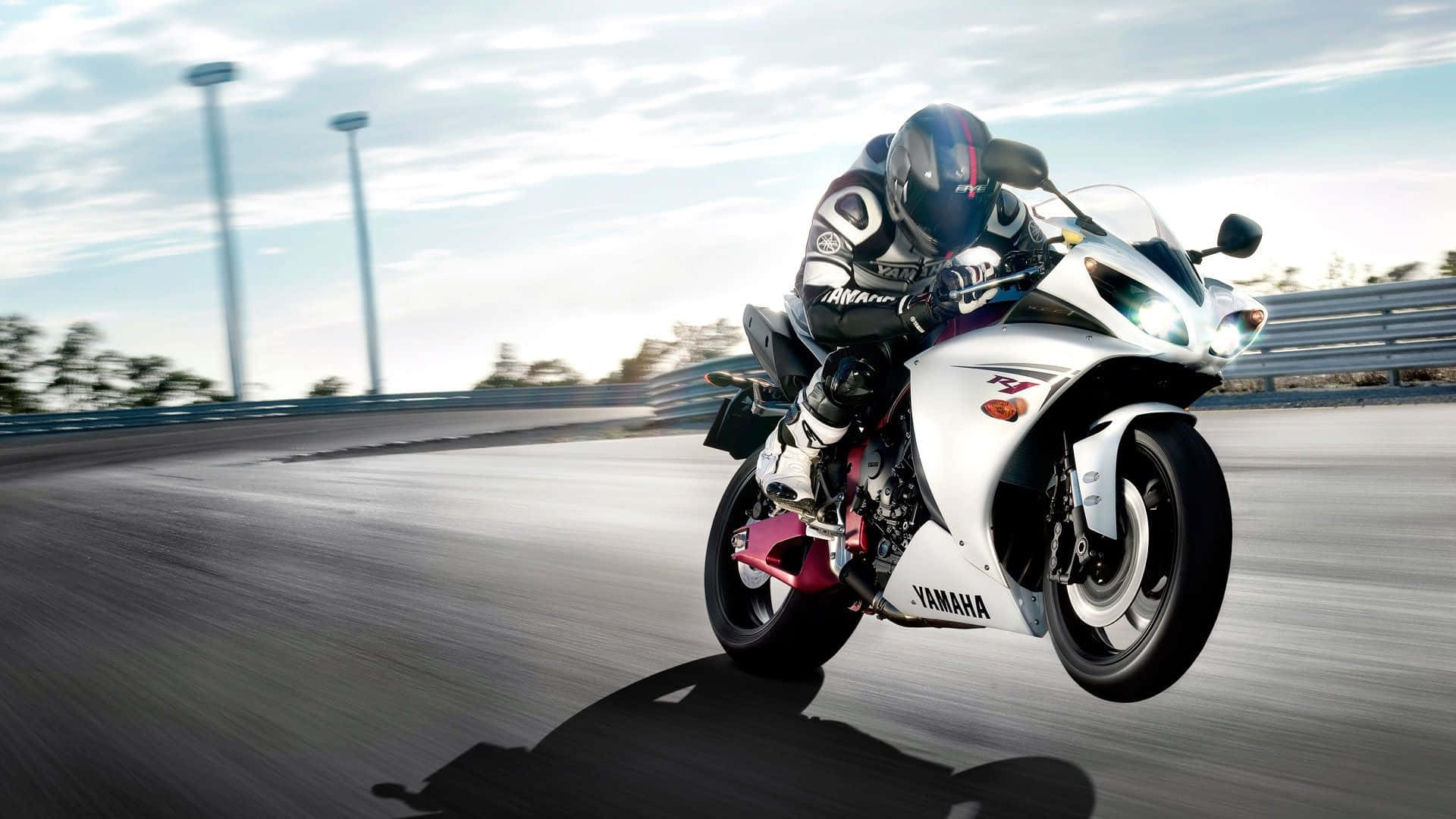 HD Bikes 桌布 壁紙 — 一名騎士在晴朗天空下的賽道上，騎著白色Yamaha跑車傾斜入彎。