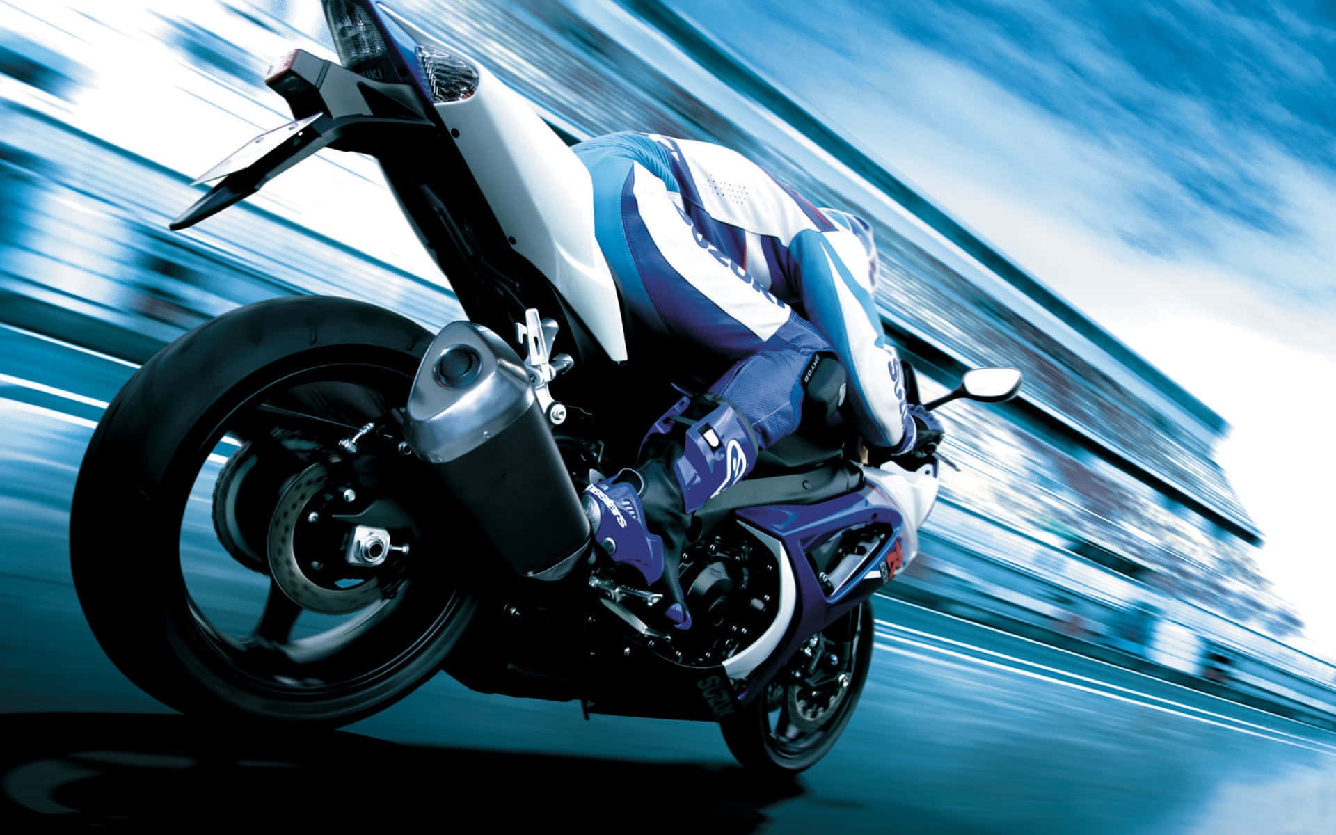 Superbike 桌布 壁紙 — 一名騎士在藍白運動機車上傾斜入急彎，帶有動態模糊痕跡。