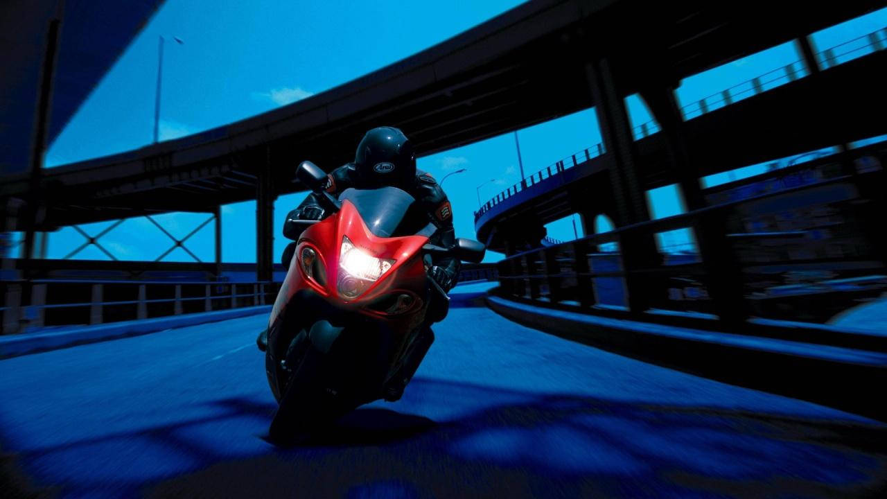 bike riding 桌布 壁紙 — 一名騎士在黃昏時分，騎著紅色運動機車，在藍色燈光的高架橋下傾斜過彎。