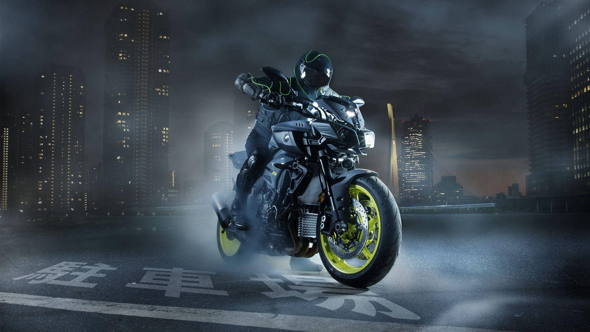機車 桌布 壁紙 — 一名騎士騎著一輛黑色摩托車，配有螢光黃色車輪，在夜晚穿過霧氣瀰漫的城市景觀，背後是發光的摩天大樓。