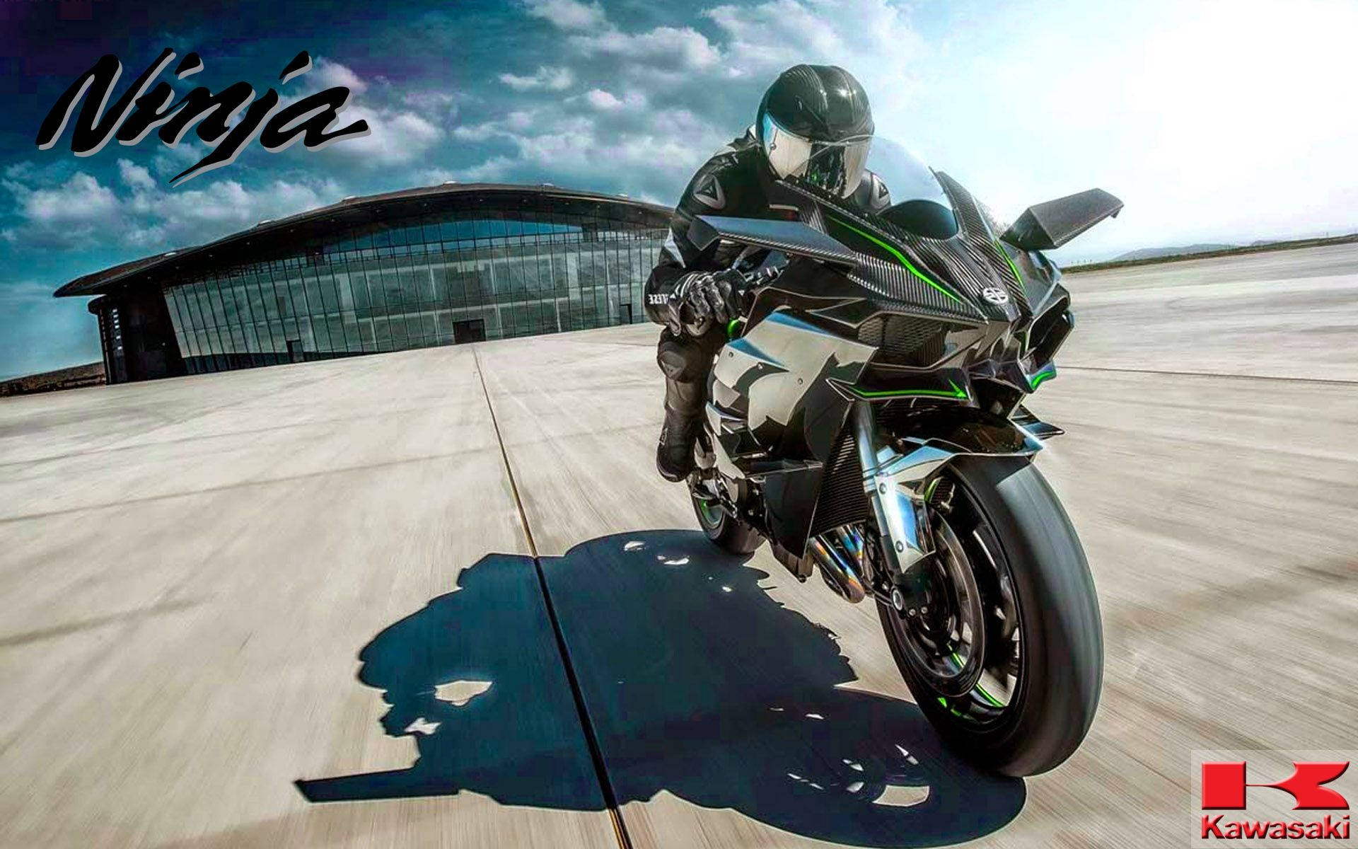 Racing 桌布 壁紙 — 一名騎士騎著黑綠色的 Kawasaki Ninja 摩托車，在戲劇性的多雲天空下，在混凝土機場上傾斜入彎。