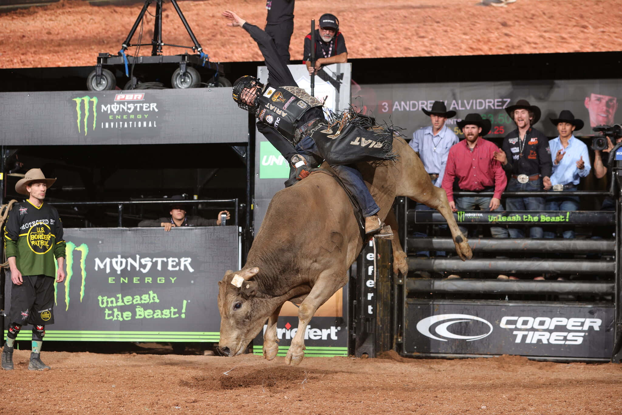 Bull Riding 桌布 壁紙 — 一名騎牛士在一個有觀眾和Monster Energy品牌的牛仔競技場中，緊緊抓住一頭跳躍的棕色公牛。