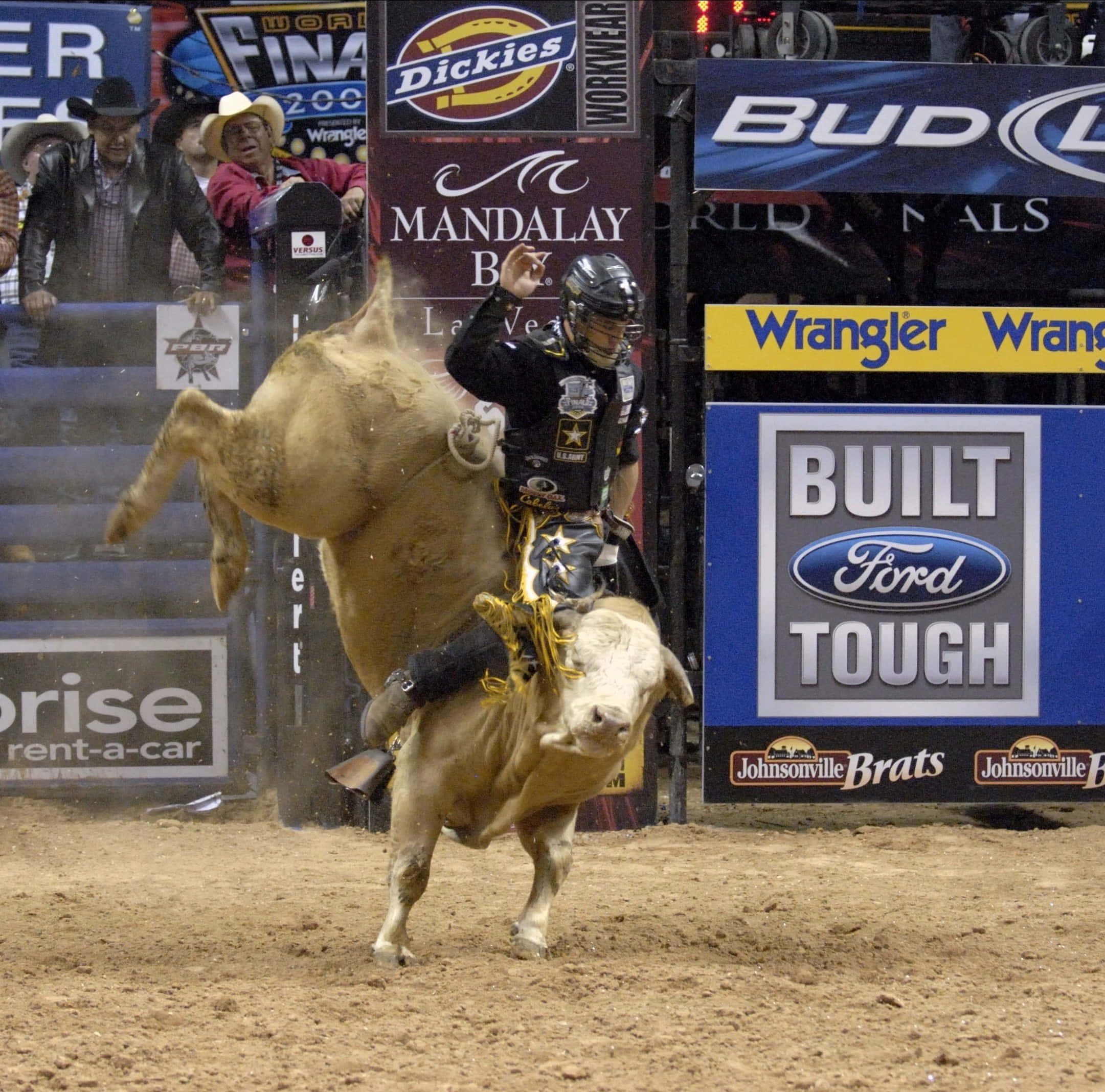Bull Riding 桌布 壁紙 — 一名騎牛士緊貼著一頭在牛仔競技場中猛烈甩動的公牛，觀眾在圍欄後觀看。