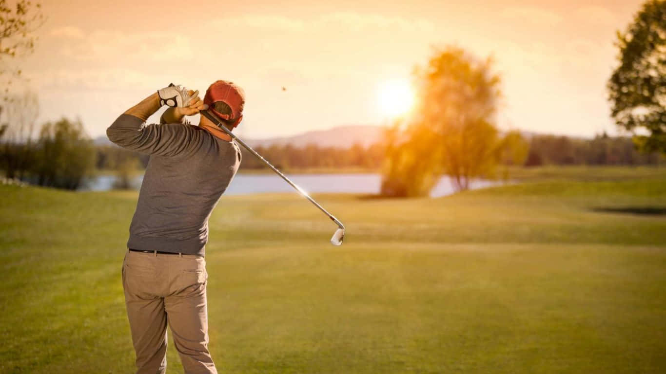 1366x768 Golf Course 桌布 壁紙 — 一名高爾夫球手在日落時分於寧靜的高爾夫球場揮桿，金色陽光與遠處樹木相伴。