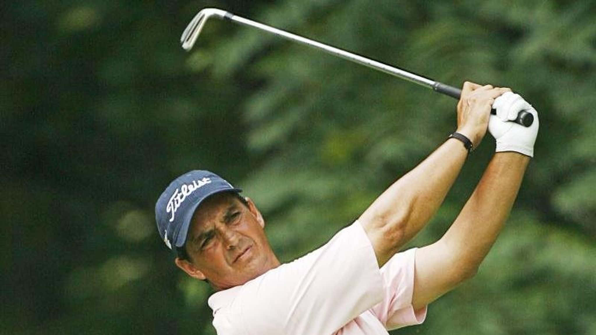 高爾夫 桌布 壁紙 — 一名高爾夫球手正在揮桿，戴著 Titleist 帽子和白色手套，背景是模糊的綠色森林。