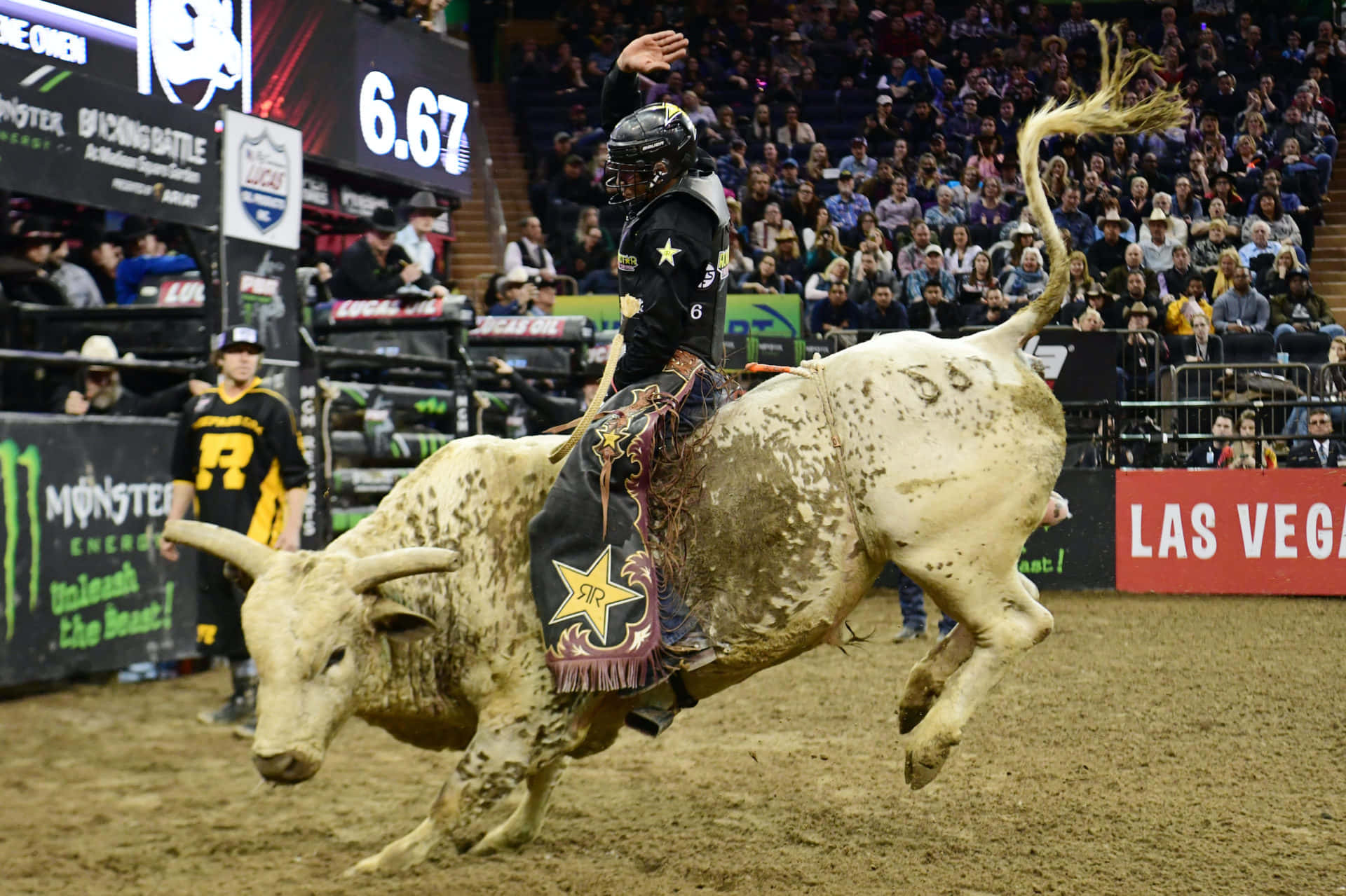 Bull Riding 桌布 壁紙 — 一名鬥牛騎士緊緊抓住一頭正在騰空跳躍的白色公牛，在擠滿觀眾的拉斯維加斯競技場中。