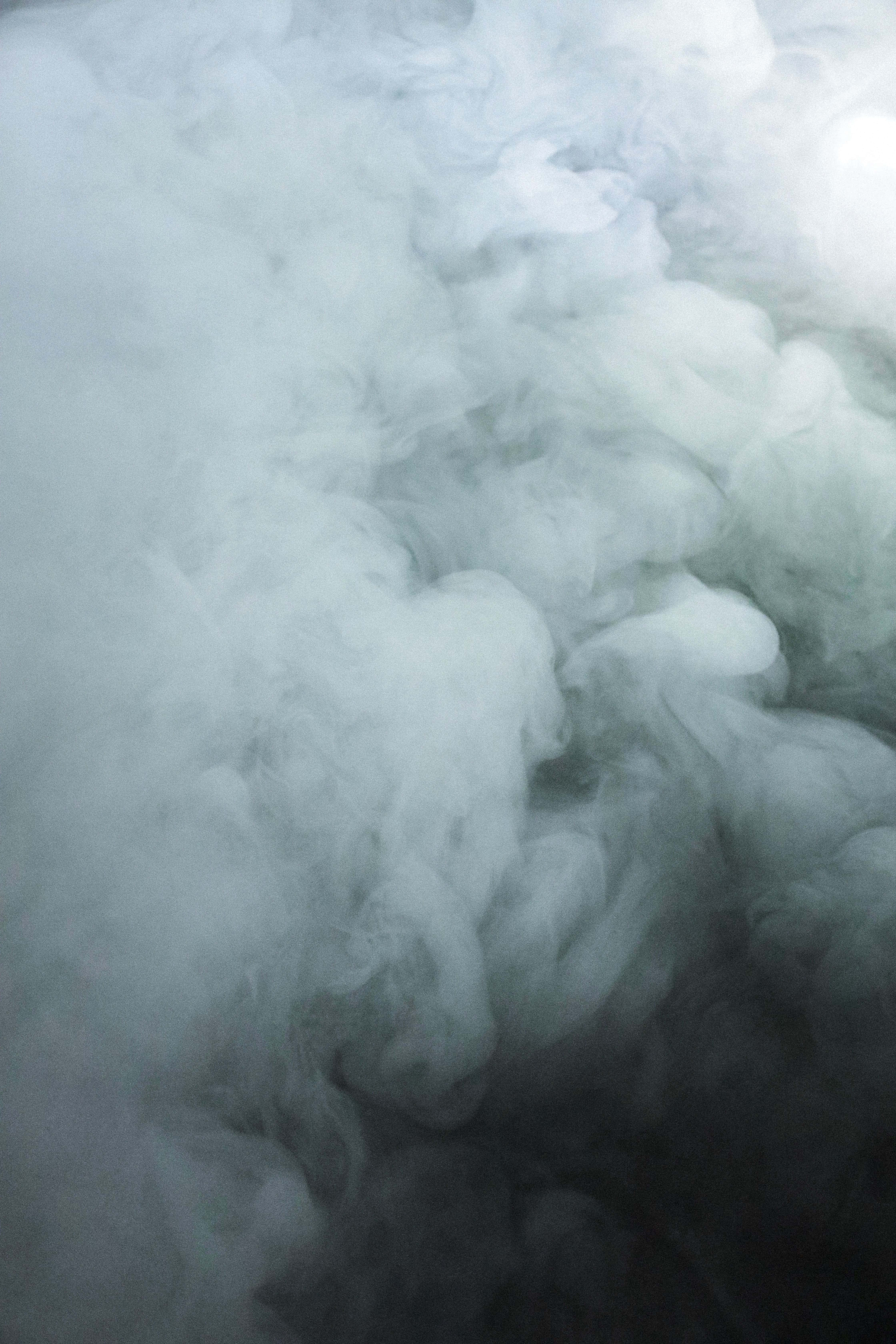Smokey 桌布 壁紙 — 一團冷色調的煙霧在黑暗背景上以白色和灰色的柔和漸變飄動。