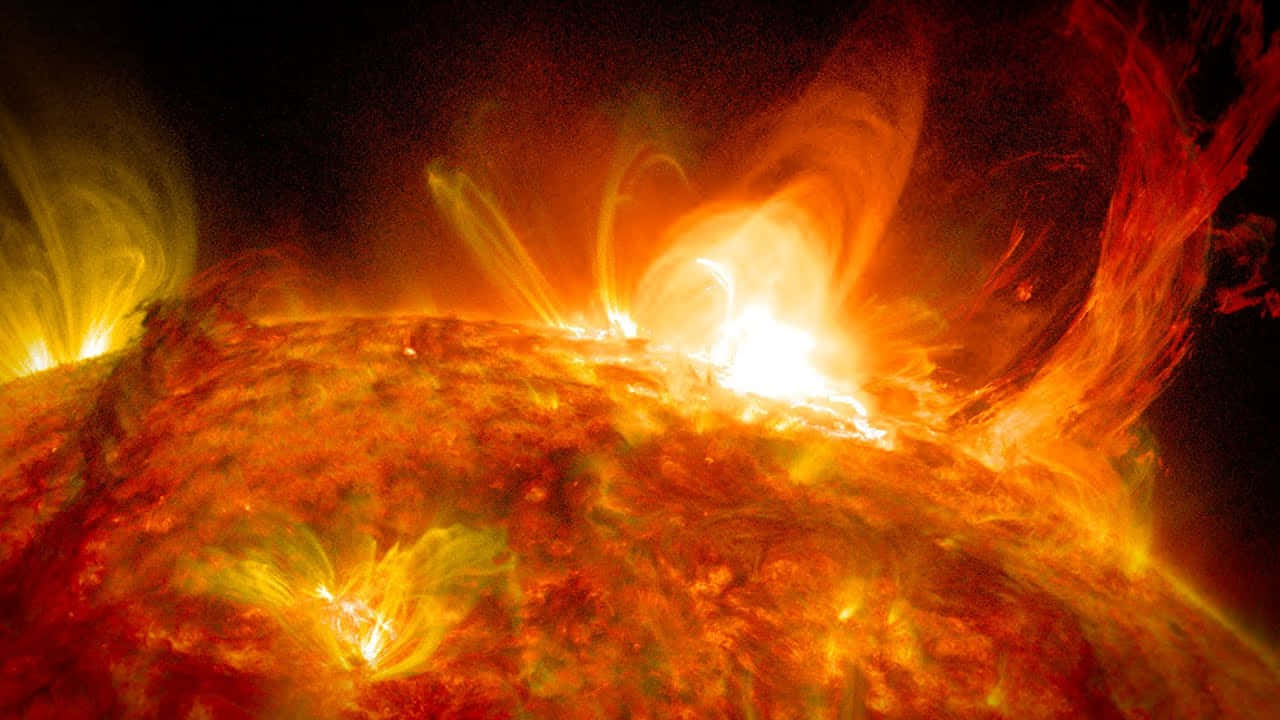 太陽 桌布 壁紙 — 一團熾熱的太陽耀斑從太陽表面噴發，發出熾熱的橙色和黃色等離子體，映襯著黑暗的虛空。