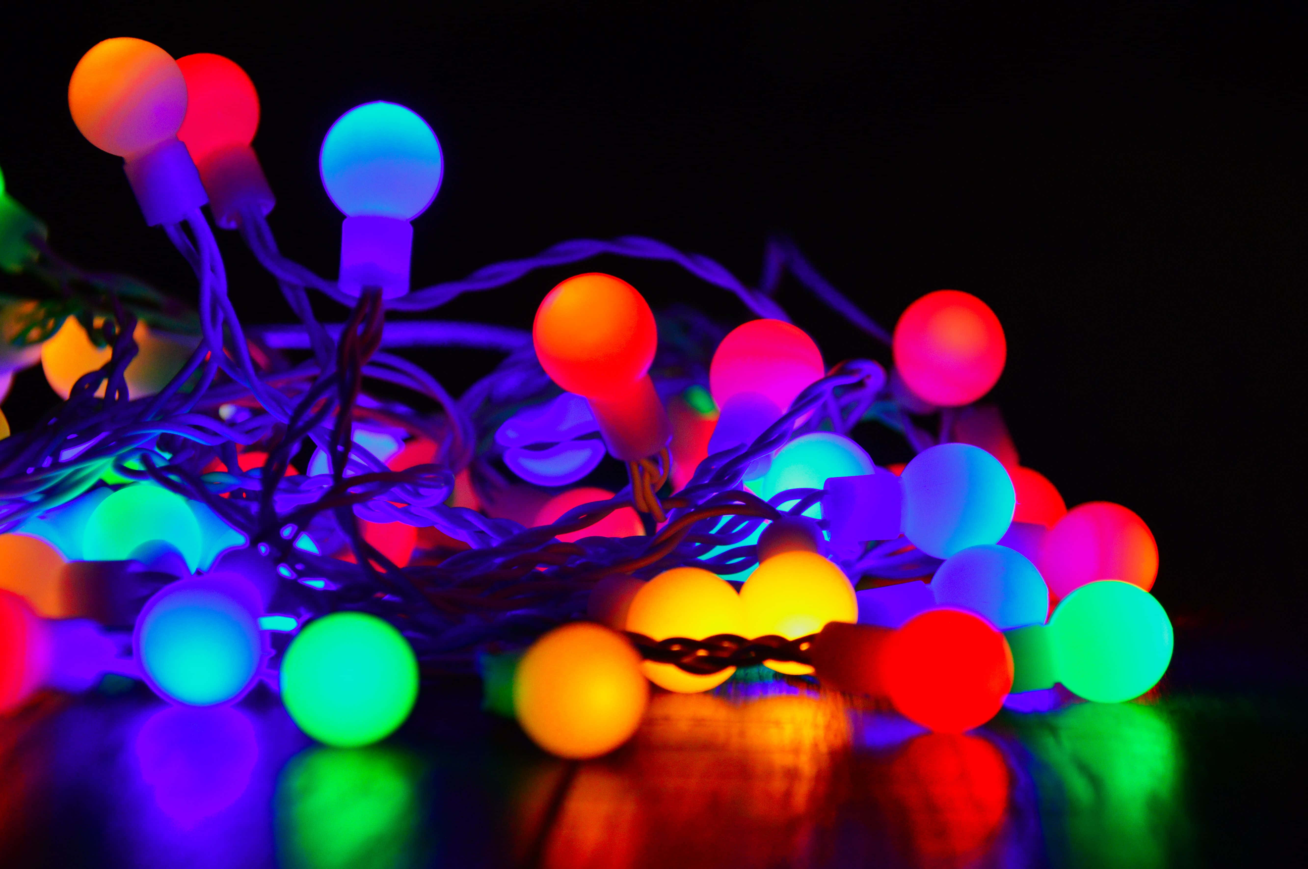 Spring Lights 桌布 壁紙 — 一團纏繞的發光多彩仙女燈在黑暗表面上投射出鮮豔的反射。