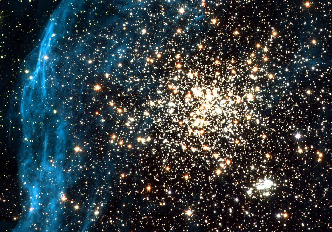 Star Cluster 桌布 壁紙 — 一團耀眼的星團在黑暗的宇宙背景下閃耀，左側有充滿活力的藍色星雲旋轉。