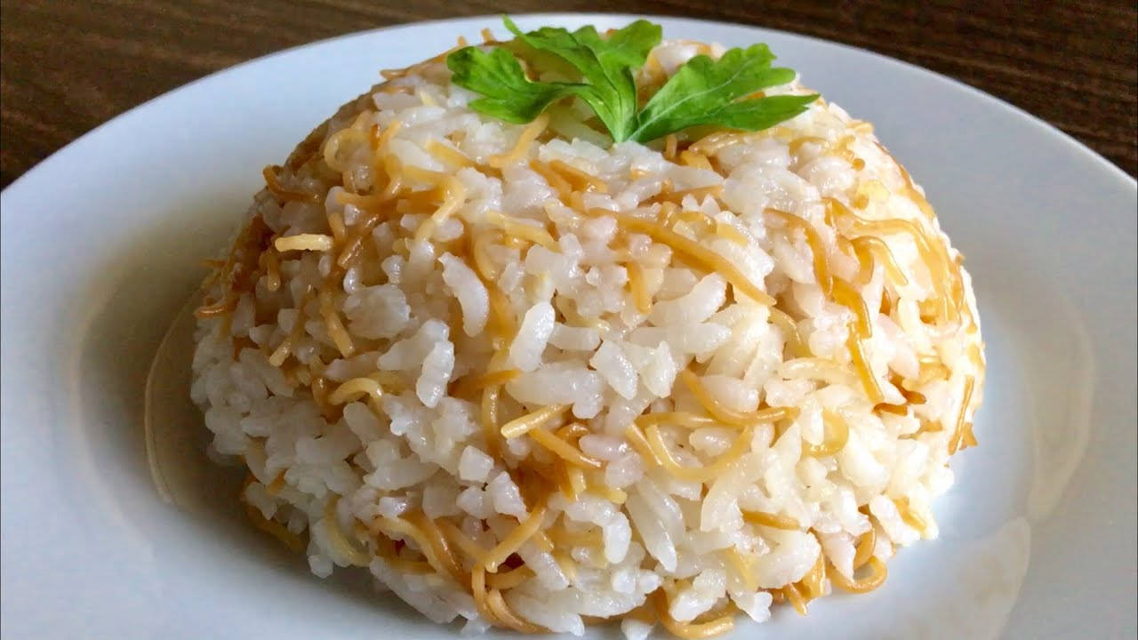 烹飪 桌布 壁紙 — 一團鬆軟白飯，上面放著金黃色炒麵和新鮮綠色歐芹葉，置於白色盤子上。