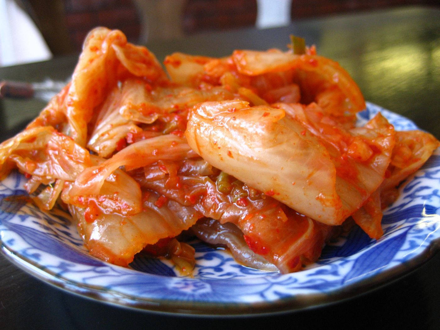 美學 桌布 壁紙 — 一團鮮豔的辣韓國泡菜在藍白圖案盤子上閃閃發光。