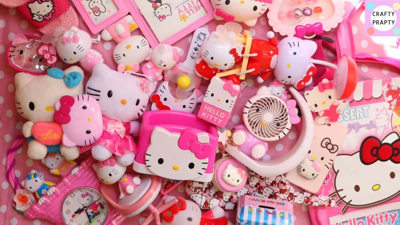 Hello Kitty 桌布 壁紙 — 一堆充滿活力的粉紅色Hello Kitty商品，包括絨毛玩具、配件和文具，以俏皮凌亂的方式排列。