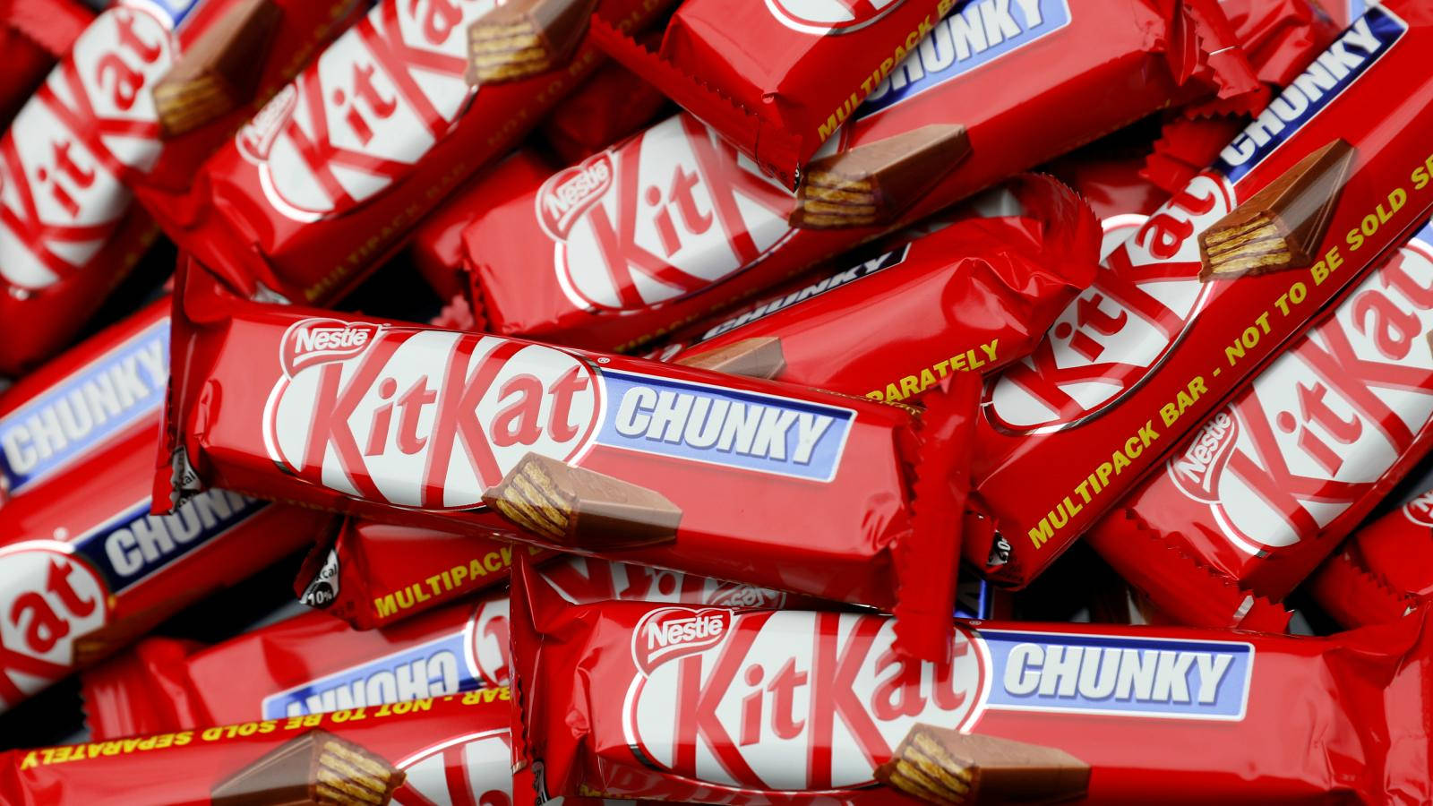 Chocolate 桌布 壁紙 — 一堆充滿活力的紅色包裝KitKat Chunky巧克力條，可見牛軋糖和巧克力碎片。