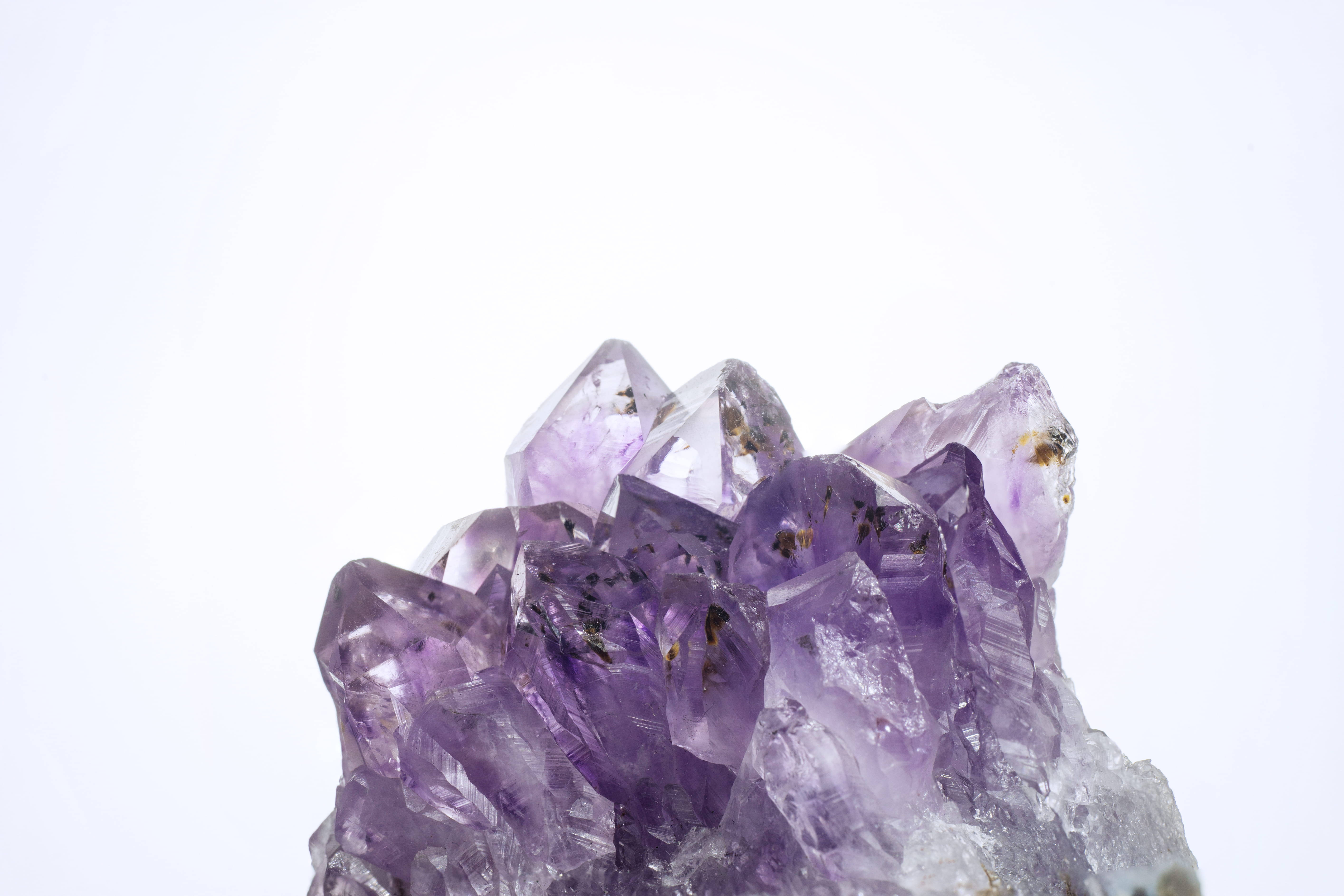 紫水晶 桌布 壁紙 — 一堆半透明紫色紫水晶晶體在純白背景上閃閃發光。
