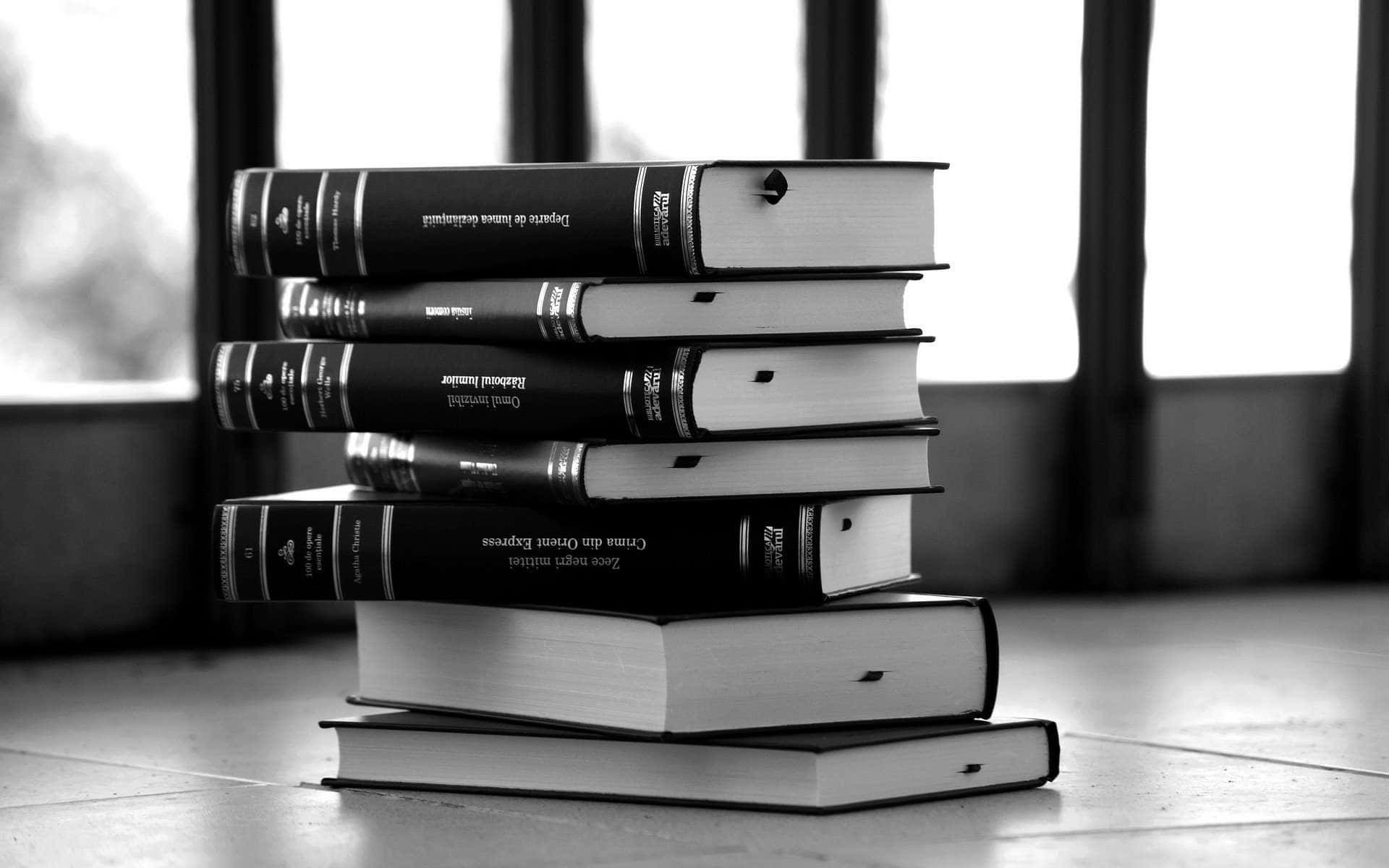 Black And White Book 桌布 壁紙 — 一堆單色厚學術書放在有垂直鐵條的窗戶附近的磁磚地上。
