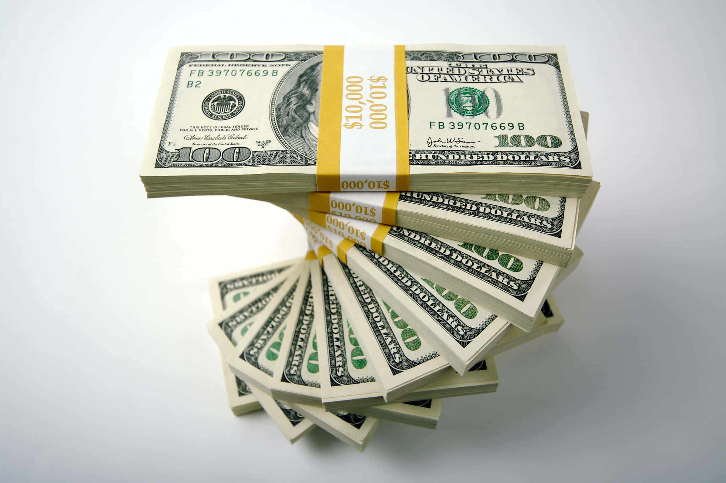 100 Dollar Bill 桌布 壁紙 — 一堆堆成捆的百元美鈔在純白背景上展開。