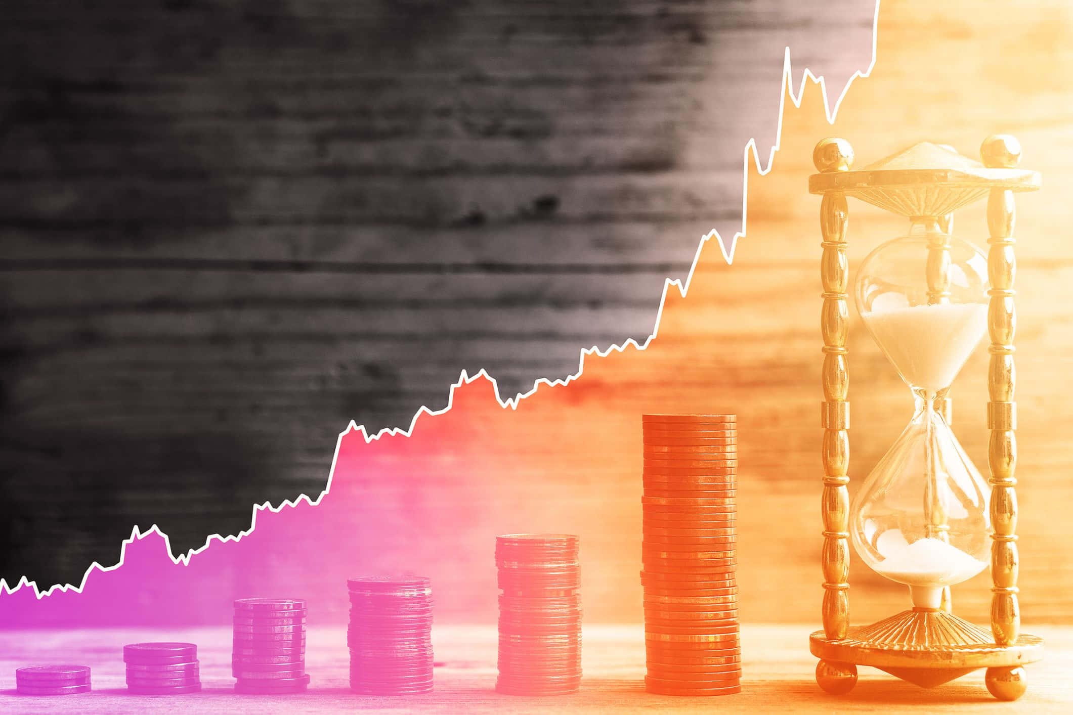 Money 桌布 壁紙 — 一堆堆硬幣隨著上升的股票圖表一起升高，沙漏在分色調的木質背景上溫暖地發光。