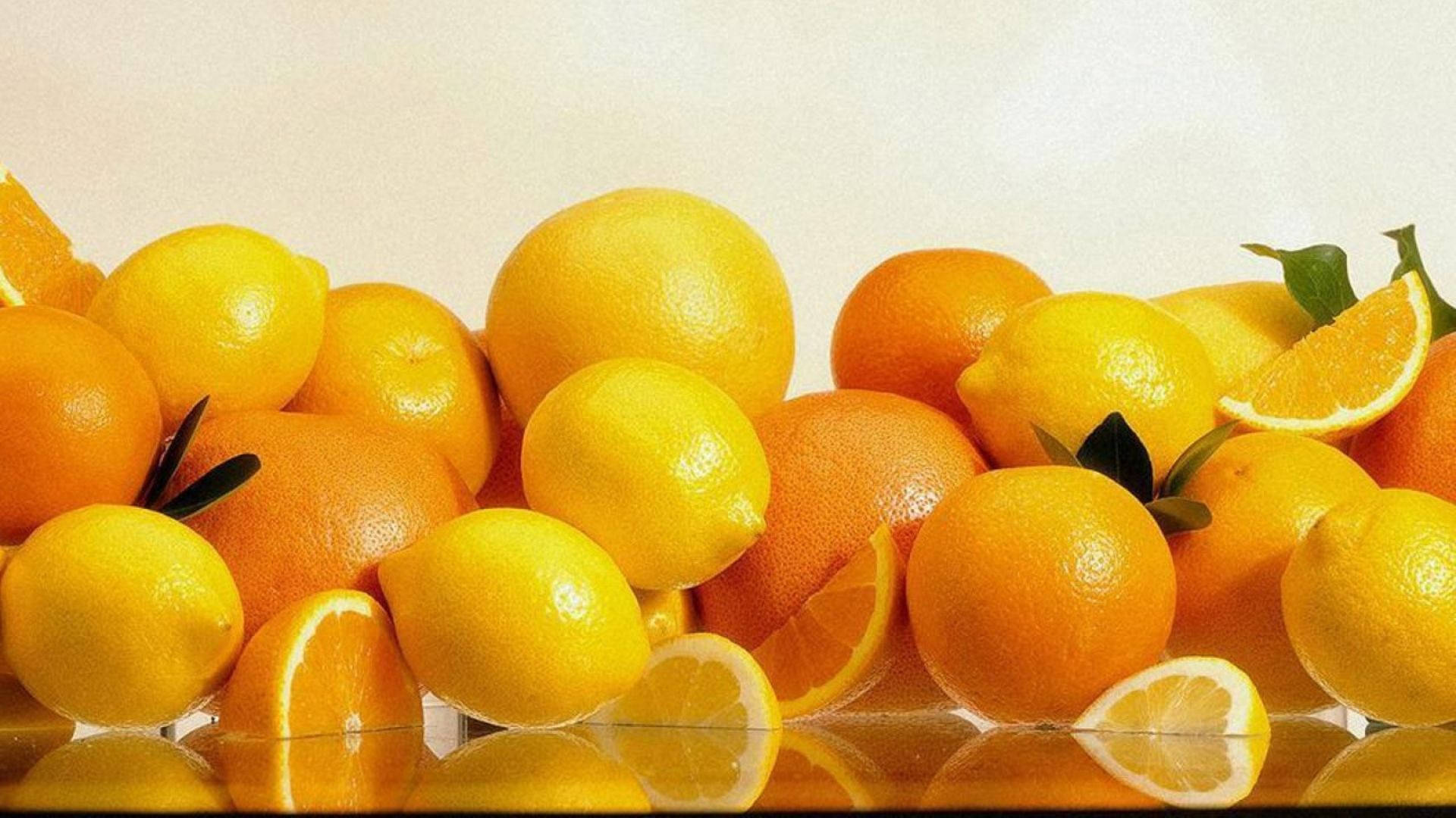Orange Fruit 桌布 壁紙 — 一堆完整和切片的柳橙和檸檬在反光表面上閃閃發光。