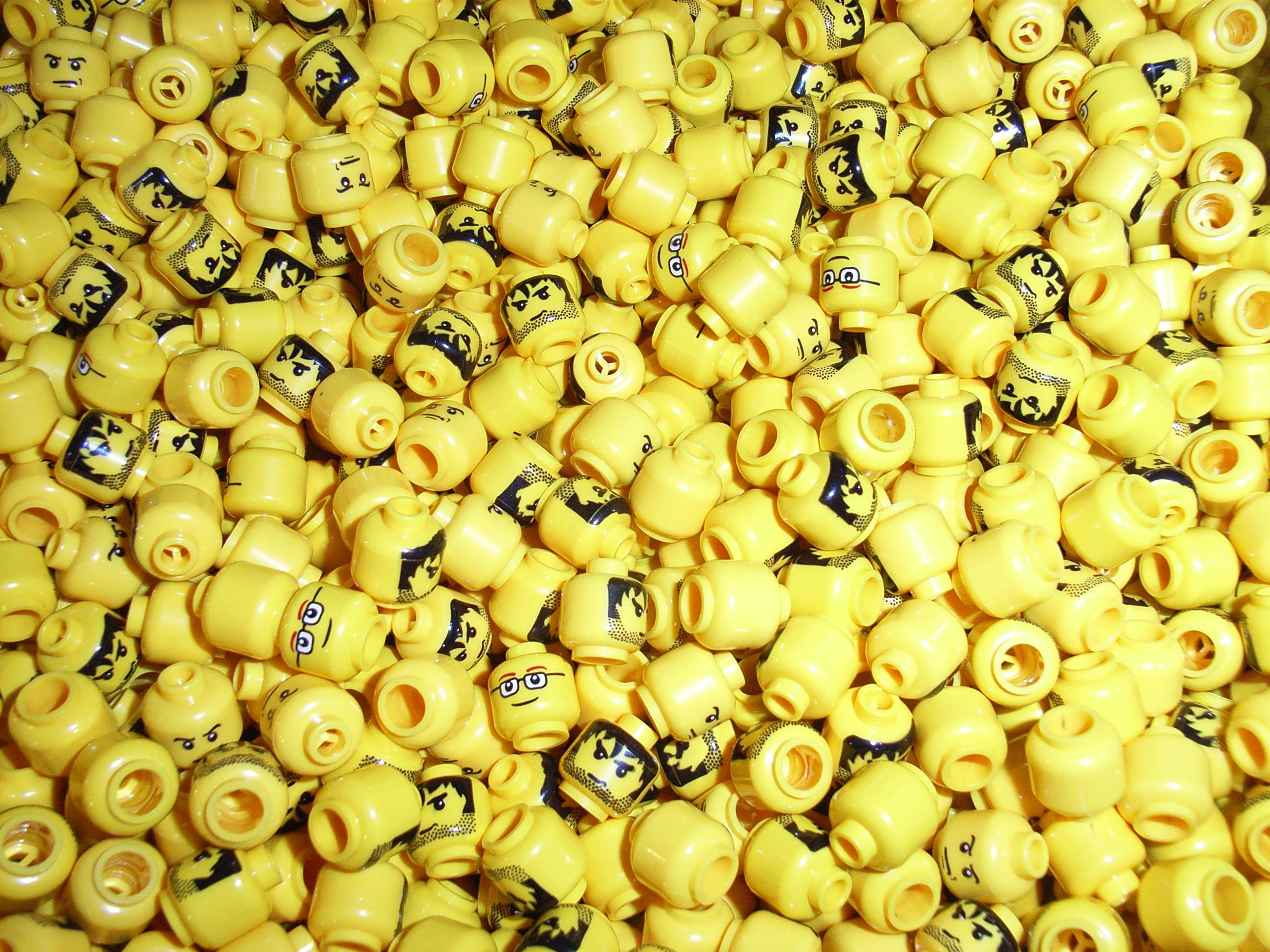 高清 桌布 壁紙 — 一堆密密麻麻的亮黃色LEGO迷你人偶頭部，上面有各種印刷的臉孔和黑色細節。