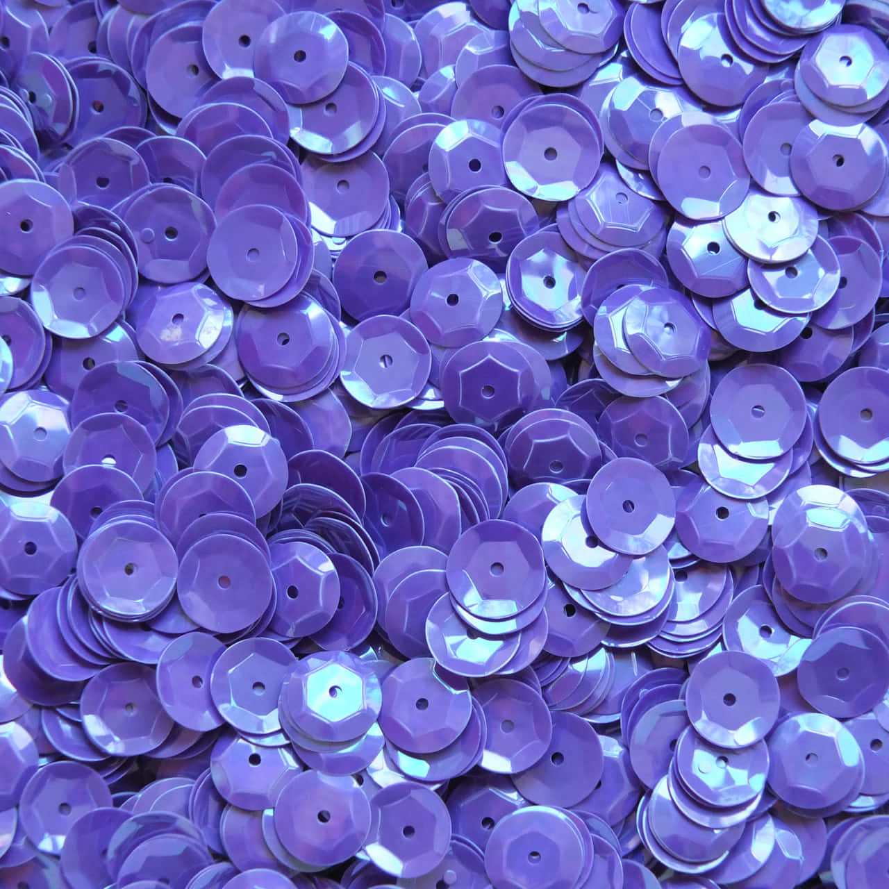 Purple Sequins 桌布 壁紙 — 一堆密集的閃亮紫色亮片，帶有切割面和中心孔，反射光線。