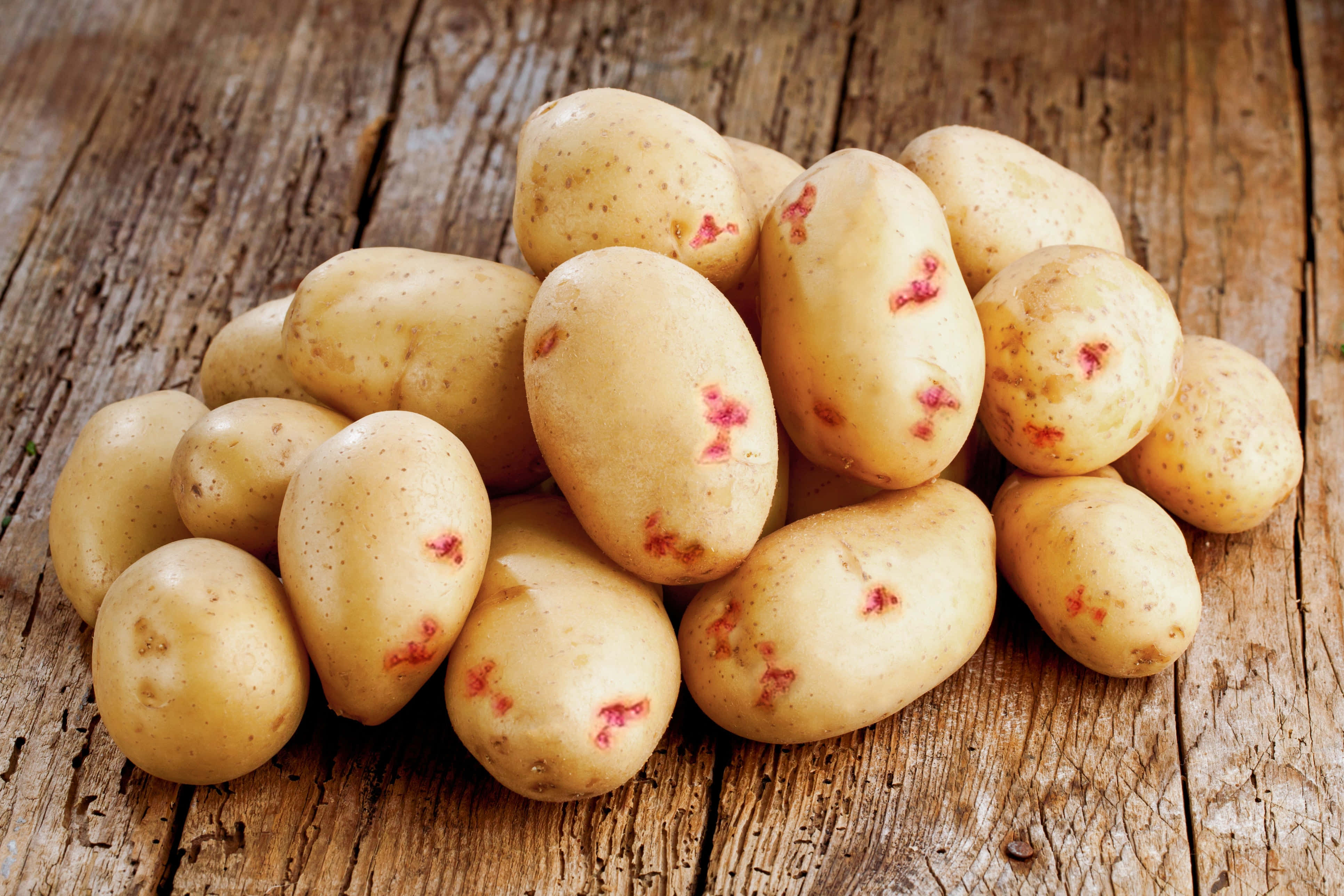 Potato 桌布 壁紙 — 一堆帶有紅點的新鮮未去皮馬鈴薯放在風化的木質表面上。