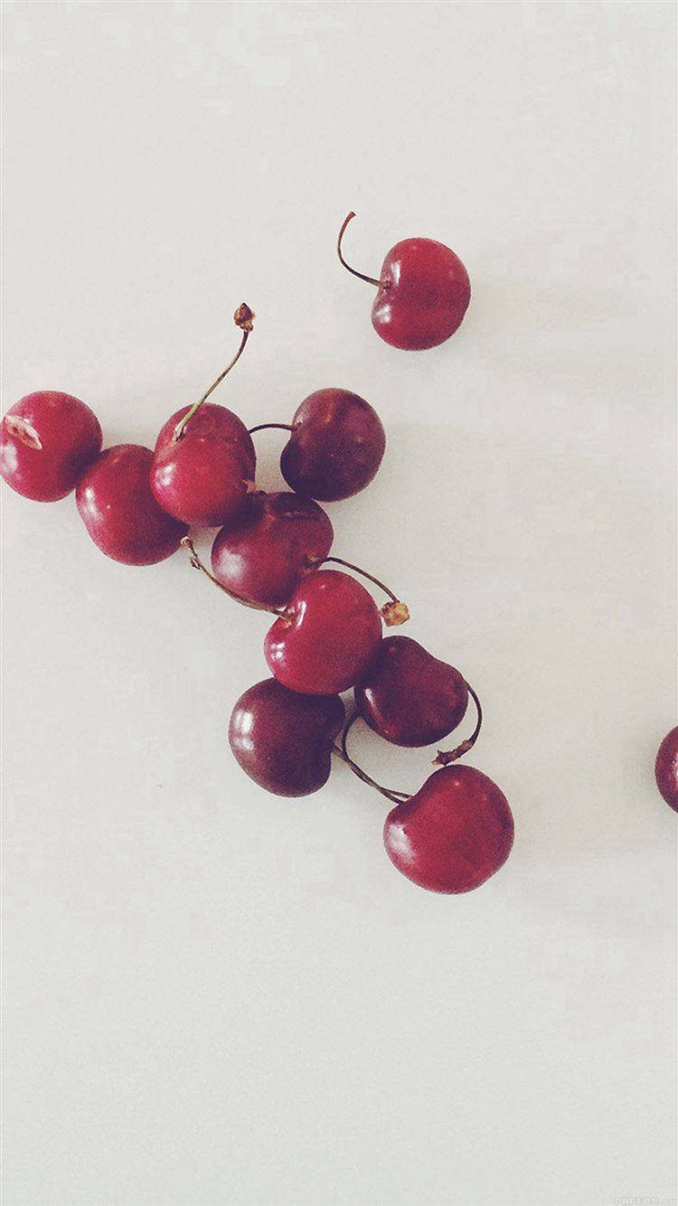 Fruit 桌布 壁紙 — 一堆帶莖的光澤紅櫻桃散落在純白表面上。