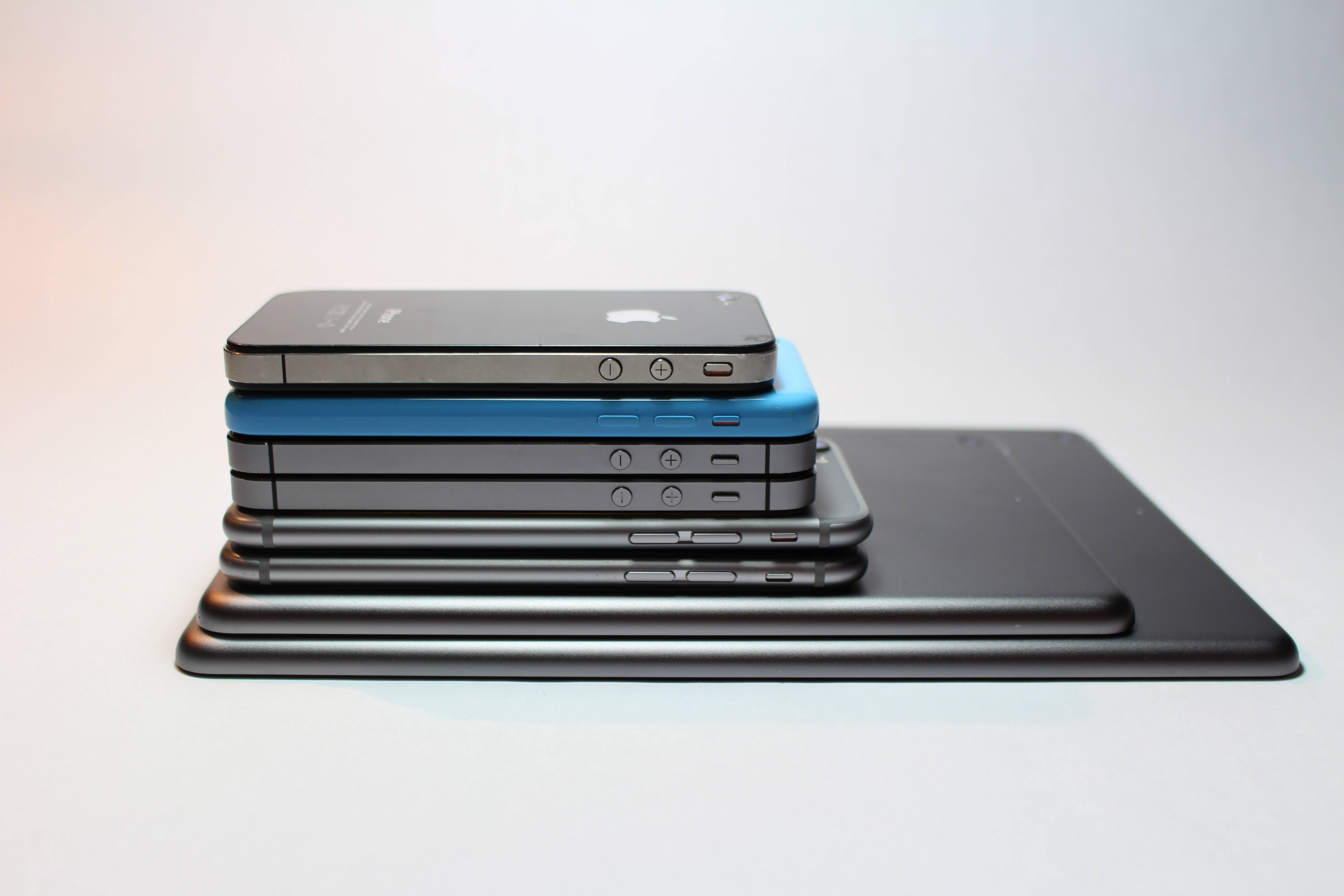酷炫iPhone 桌布 壁紙 — 一堆復古智慧型手機和平板電腦，採用時尚的黑色和藍色色調，背景為純白色。