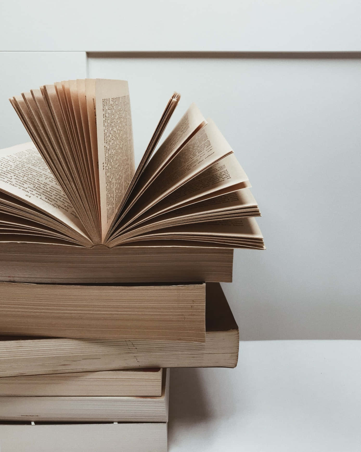 Aesthetic Book 桌布 壁紙 — 一堆復古書籍，其中一本打開，露出泛黃的書頁，背景為簡約白色。