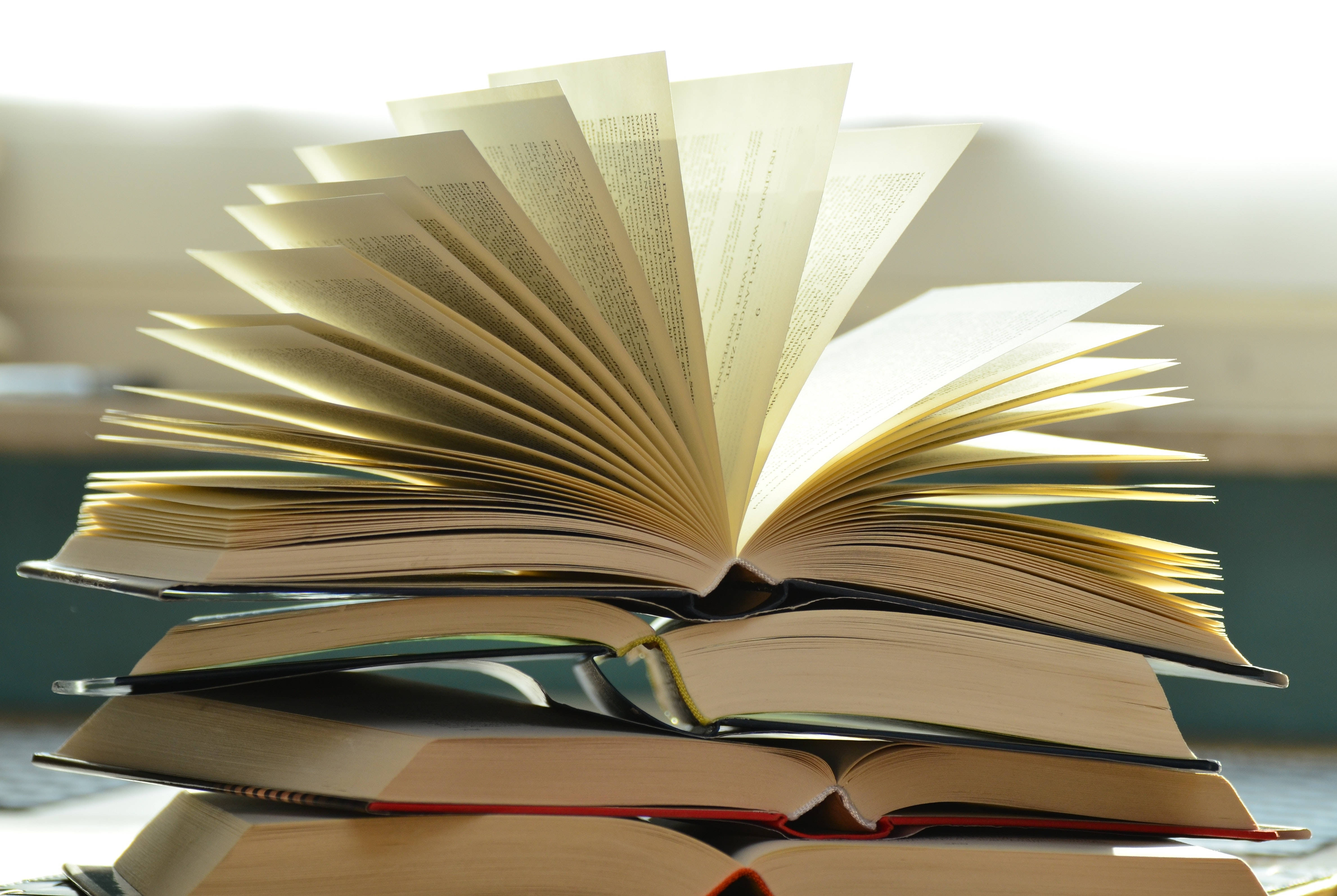 讀書動力 桌布 壁紙 — 一堆打開的書本像翅膀般展開，沐浴在溫暖的金色光芒中。