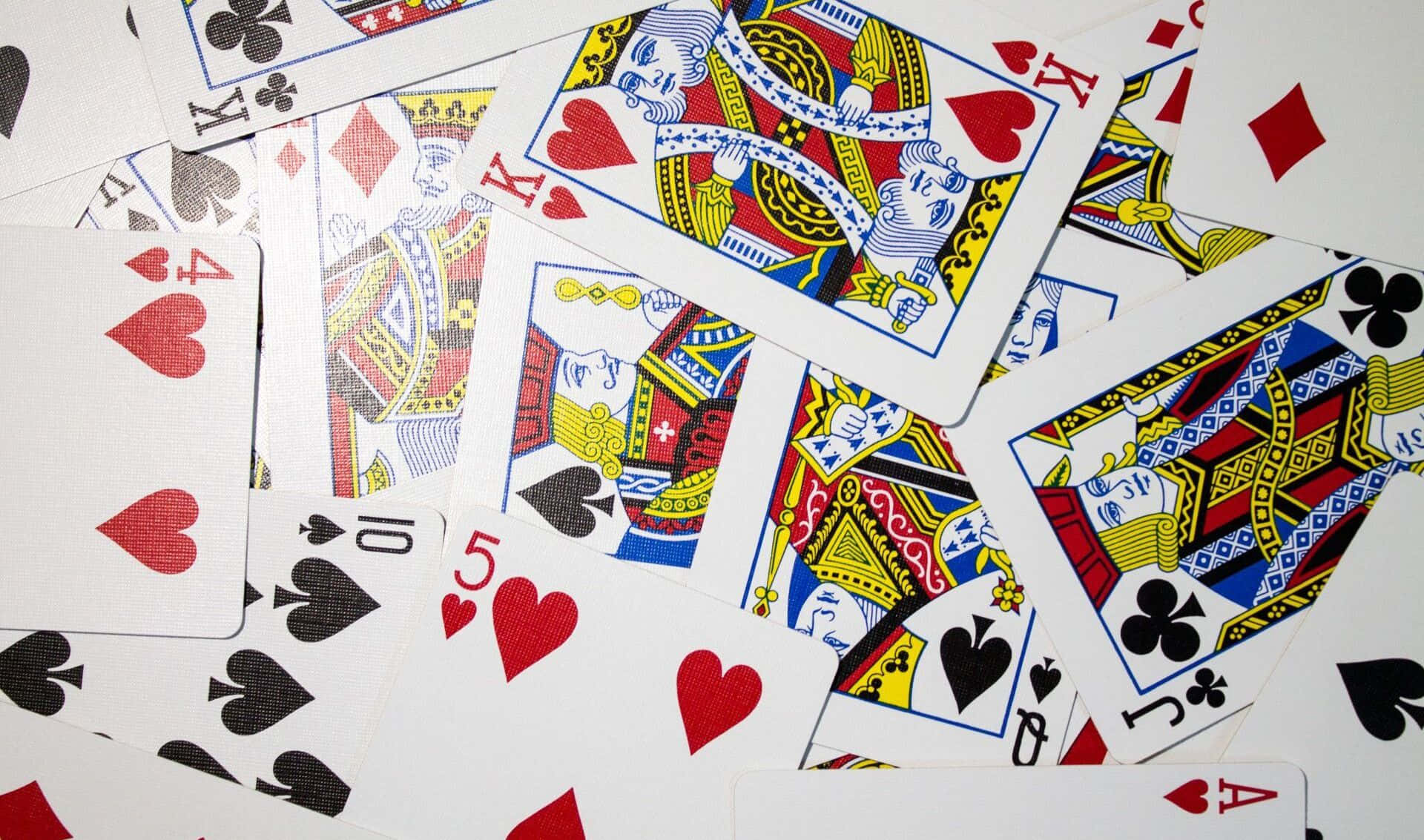 Card Games 桌布 壁紙 — 一堆散落在純白表面上的彩色撲克牌，上面有皇室人物和編號花色。