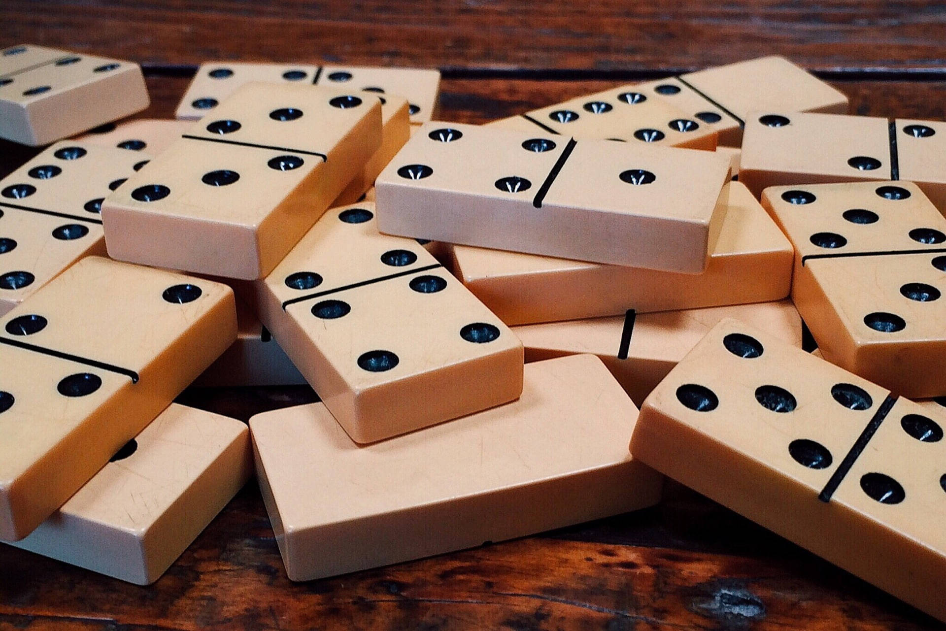 Domino 桌布 壁紙 — 一堆散落的奶油色黑點骨牌放在深色木質表面上。