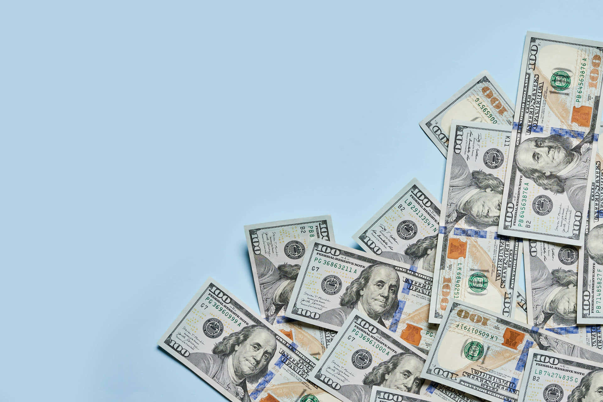 Money Falling 桌布 壁紙 — 一堆散落的百元美鈔放在純淺藍色背景上，留有充足的負空間。
