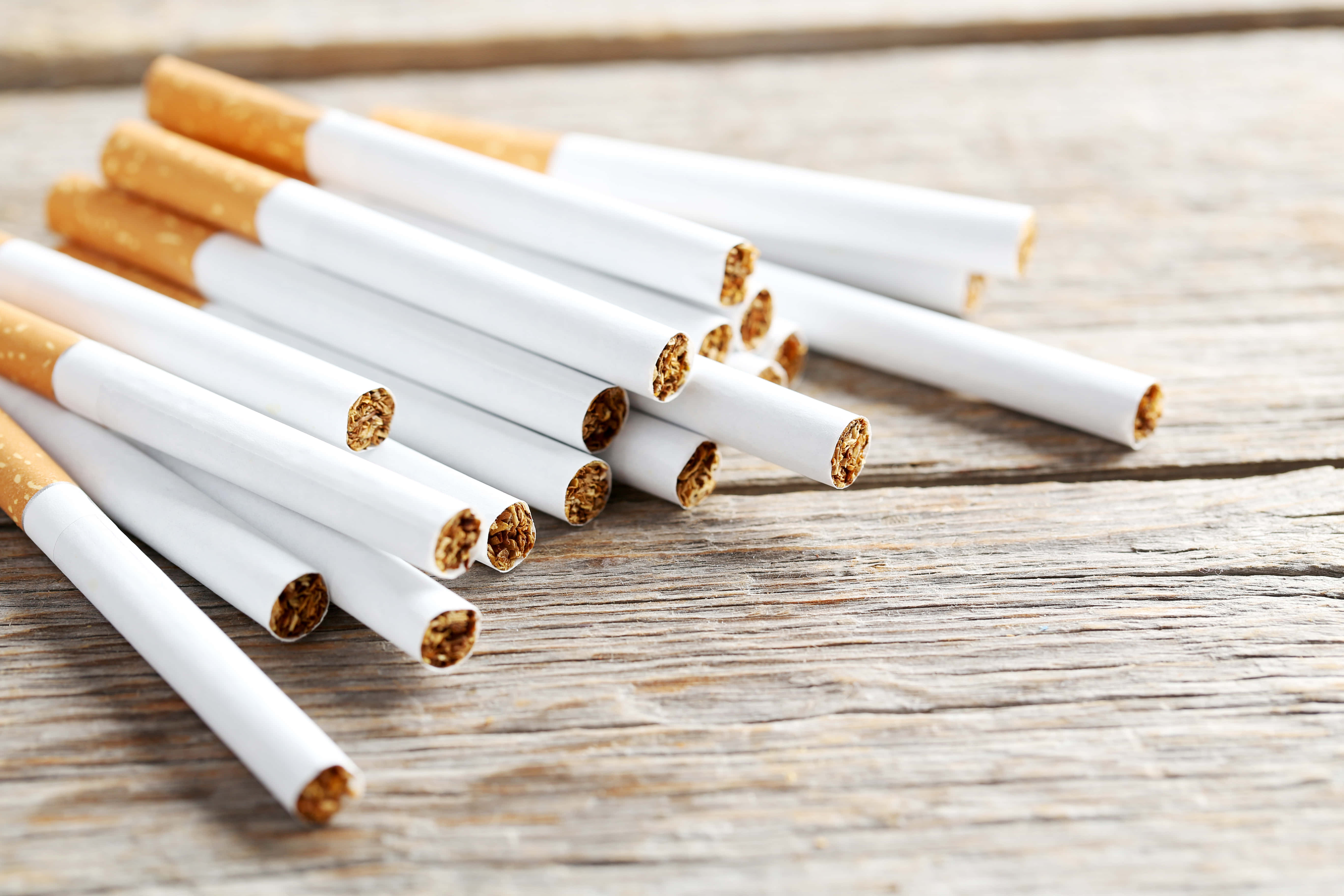 cigarettes 桌布 壁紙 — 一堆散落的香菸，切口朝下，放在經風化的木質表面上。