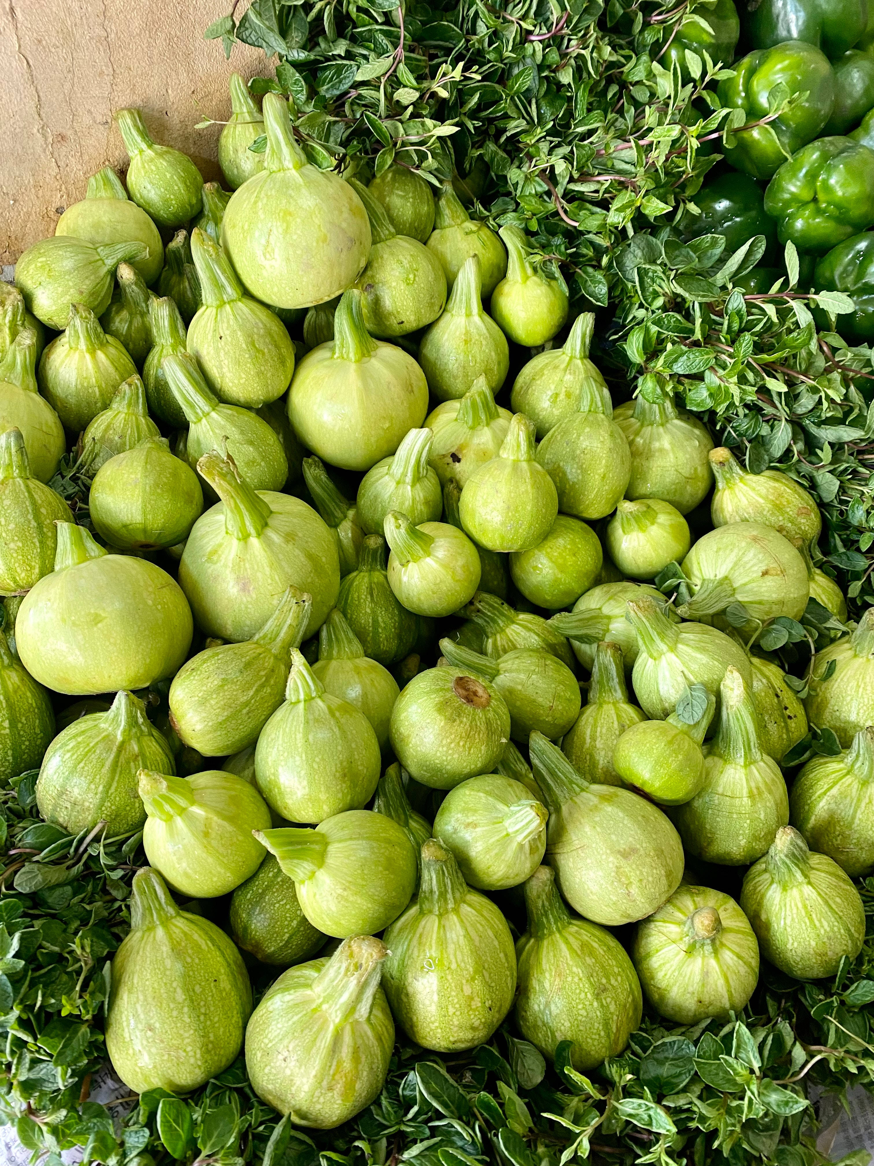 Vegetables 桌布 壁紙 — 一堆新鮮的綠色無花果，夾雜在茂密的綠葉中，在市場攤位上。