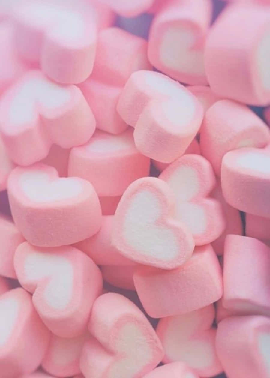 Heart Shape 桌布 壁紙 — 一堆柔軟的粉紅色心形棉花糖，帶有白色中心，在柔和光線下閃耀。