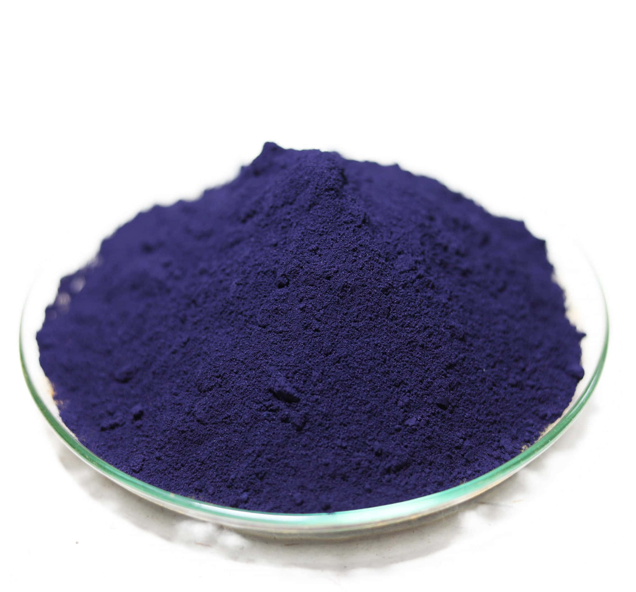 Indigo Blue 桌布 壁紙 — 一堆深紫色粉末放在透明玻璃碟中，背景為純白色。