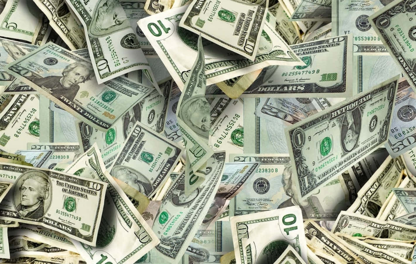 金錢 桌布 壁紙 — 一堆混亂散落的美國美元鈔票，各種面額，形成密集的金錢背景。