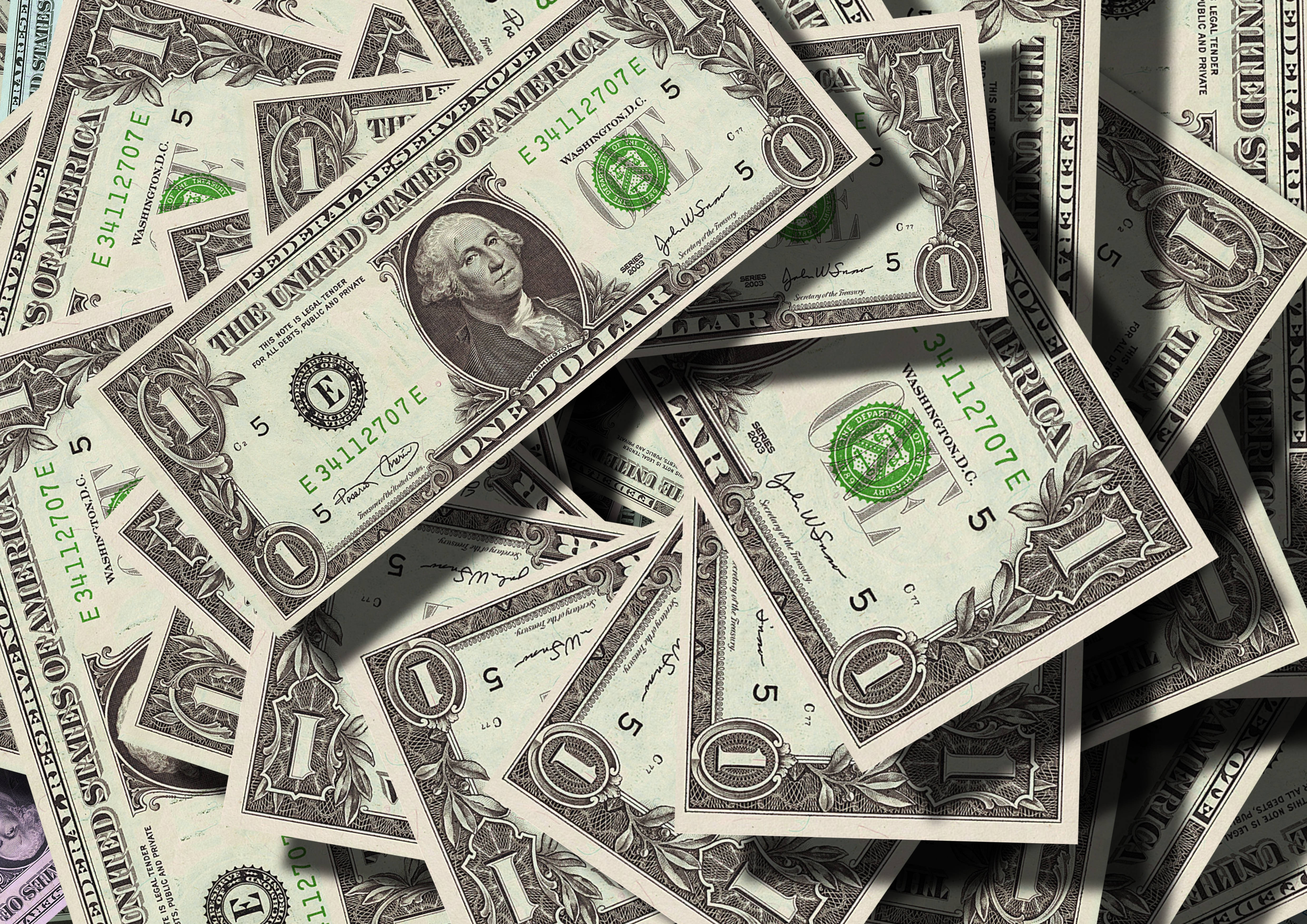 No Money 桌布 壁紙 — 一堆混亂的一美元鈔票散落在重疊的層次中，尖銳的陰影投射在它們的綠色和白色表面上。