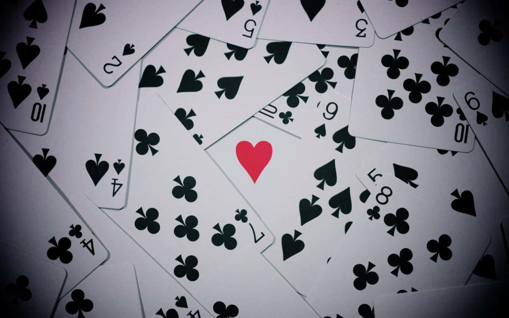 Poker 桌布 壁紙 — 一堆混亂的撲克牌，其中一張紅色愛心牌在黑色花色中脫穎而出。