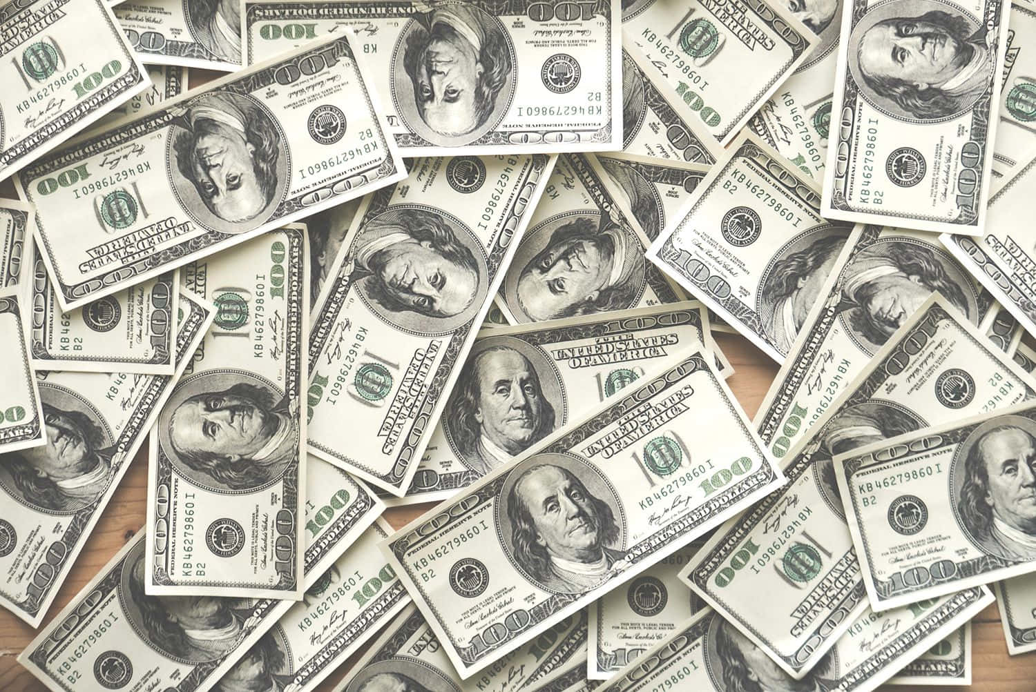 金錢 桌布 壁紙 — 一堆混亂的百元美鈔散落在木質表面上。